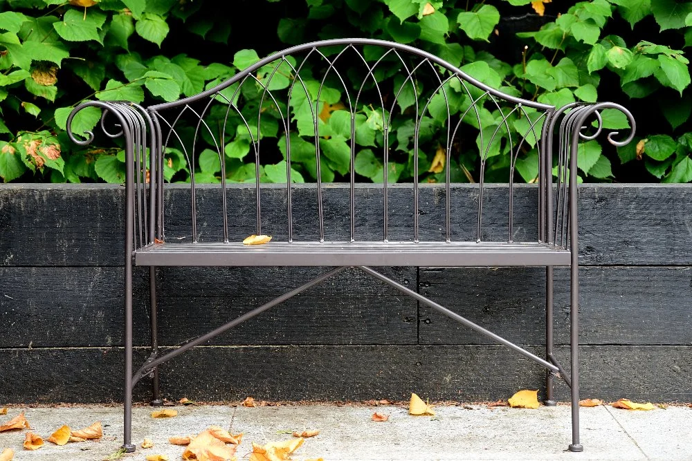 Ornate metal bench against black timber wall, Wimbledon garden by Jane Shankster Garden Design

An ornate metal bench with scrolled armrests sits against a black-painted timber wall and a backdrop of glossy green foliage. This considered furniture ch