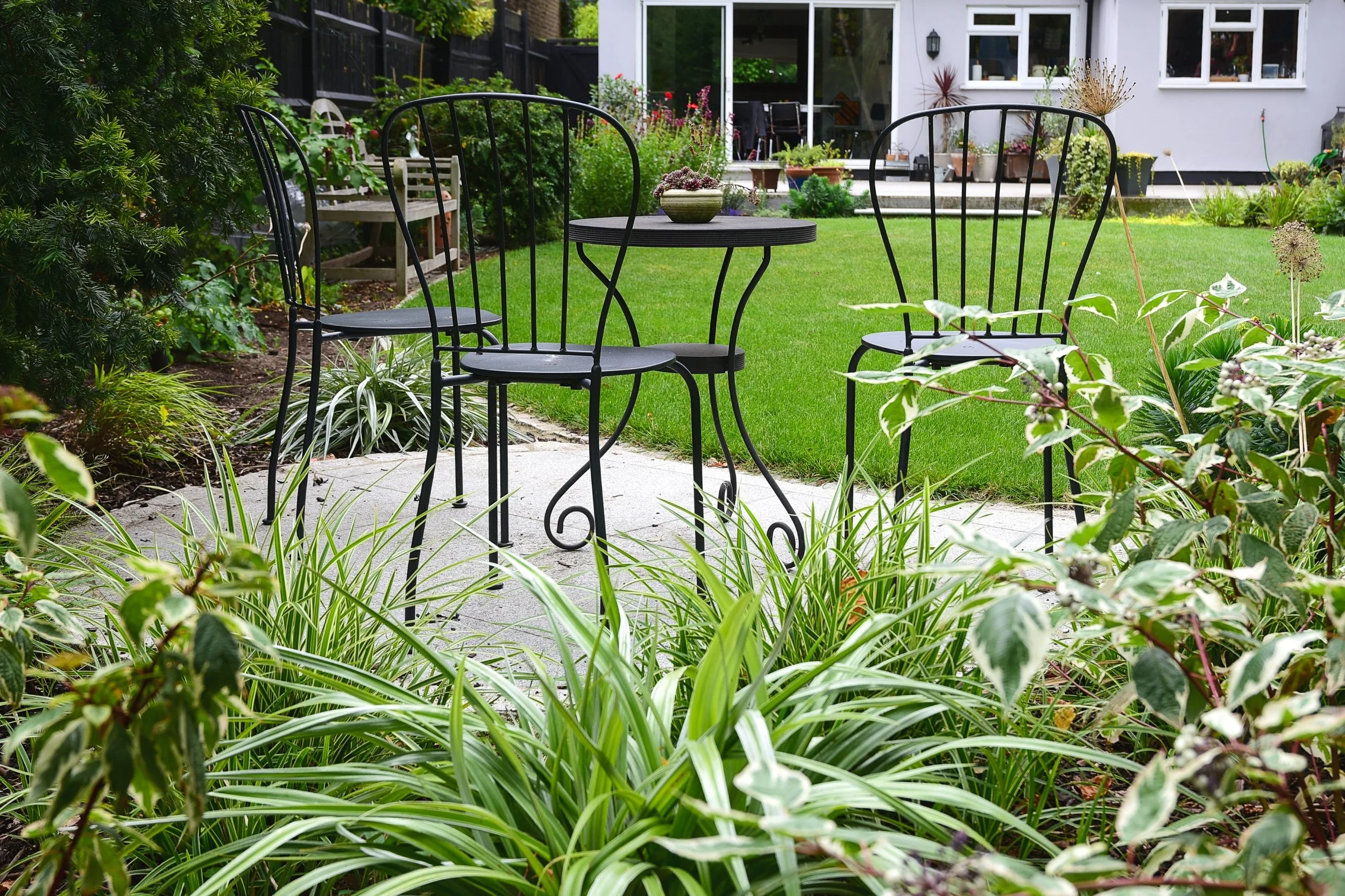 Bistro table and chairs with view back to the house in Wimbledon.
Small seating area with a view of the garden and house in this garden for entertaining designed by Jane Shankster Garden Design