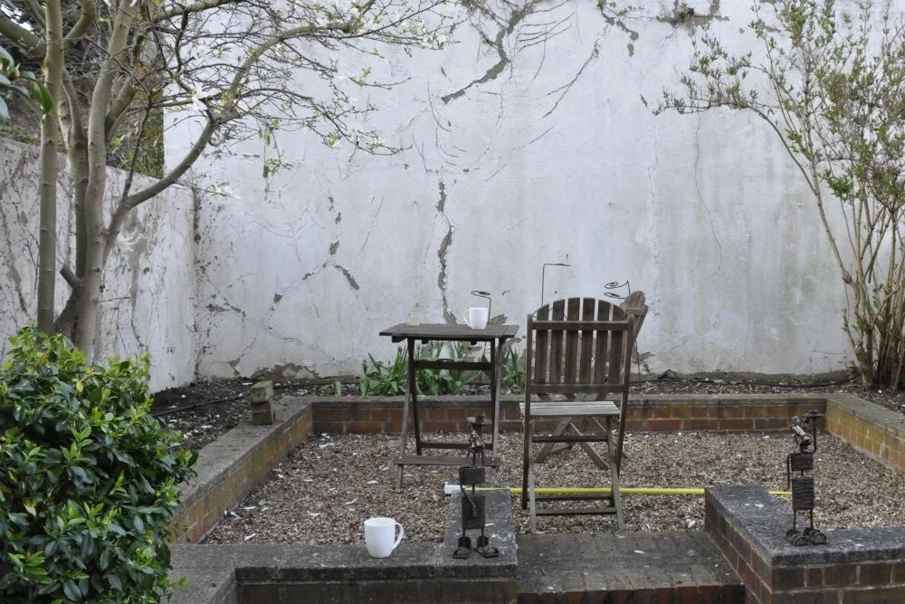 A view of a dark dingy courtyard in Blaham before being transformed

Grey, cracked walls with dead and dying plants created a gloomy space before being redesigned by JaneShanksterGardenDesign.co.uk