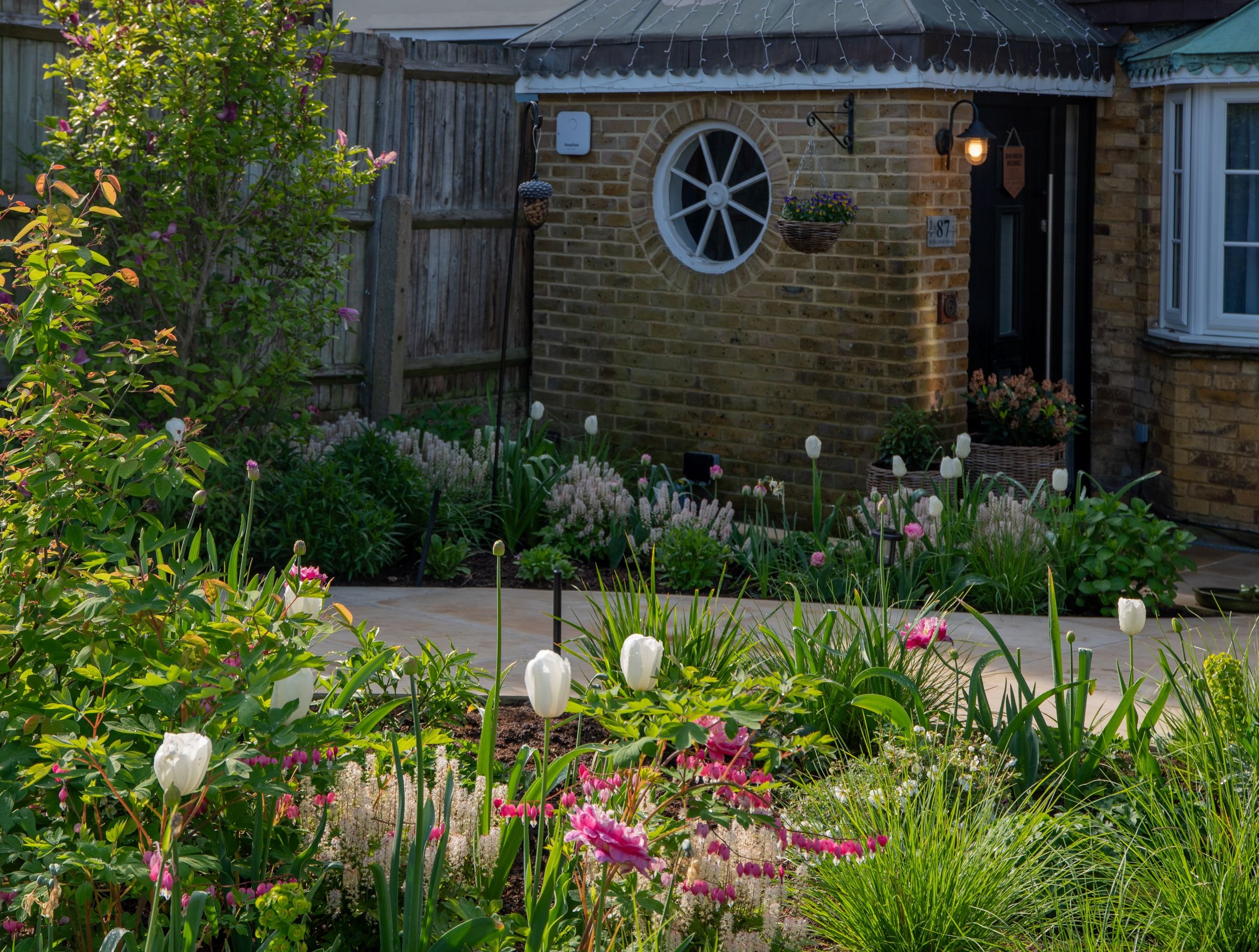 A Raynes Park front garden path leading to the entrance, framed by tulip, tiarella and bleeding heart borders. JaneShanksterGardenDesign.co.uk

The paved path curves towards the front door, flanked by generous borders of tulips, tiarella and bleeding