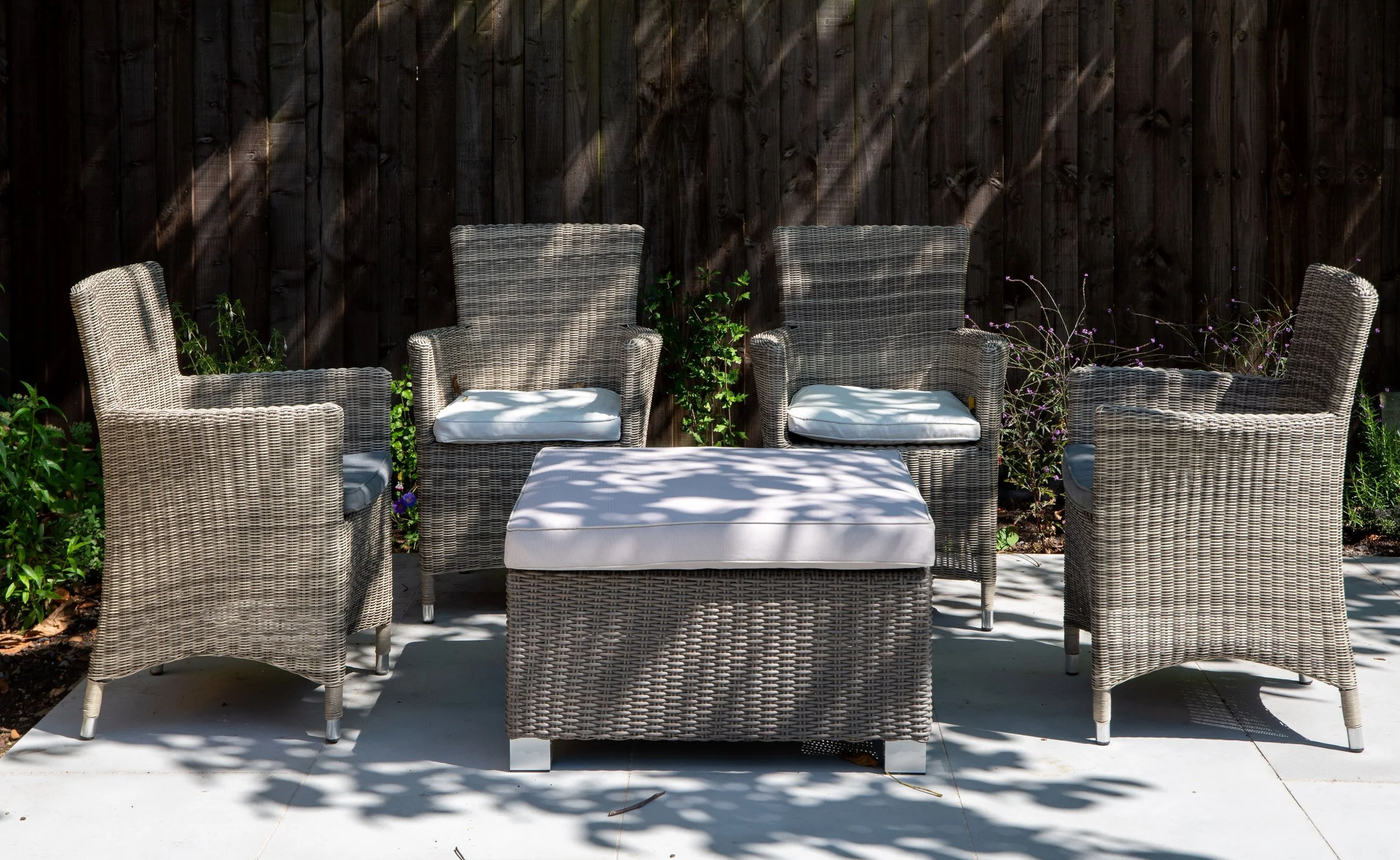 Rattan armchairs and footstool in communal garden seating area, property development

A shaded seating nook within a communal garden for a property development, featuring woven rattan armchairs and a matching footstool arranged around light stone pav