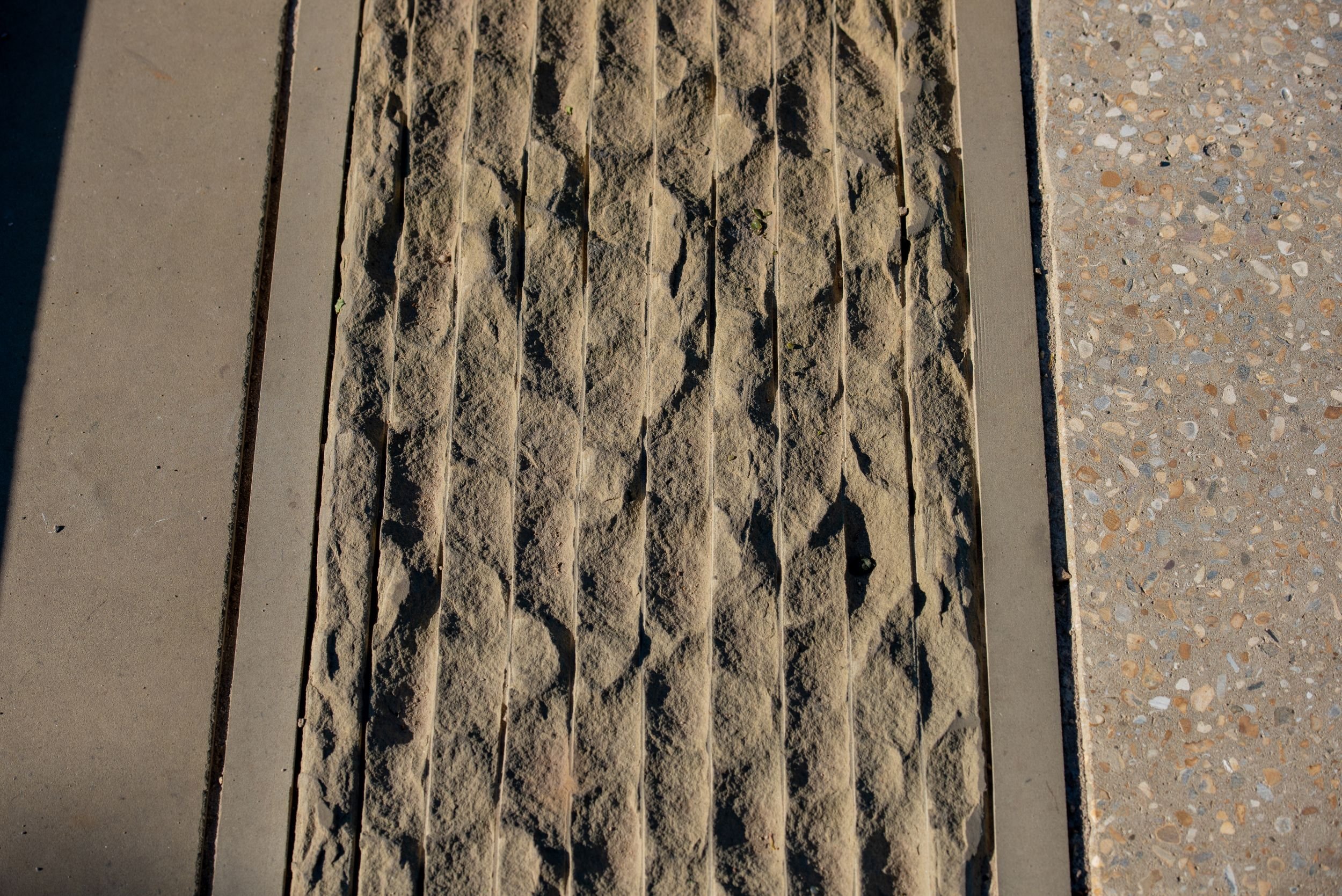 Close-up detail of ribbed sandstone paving beside concrete edging in the Queen Elizabeth II Garden