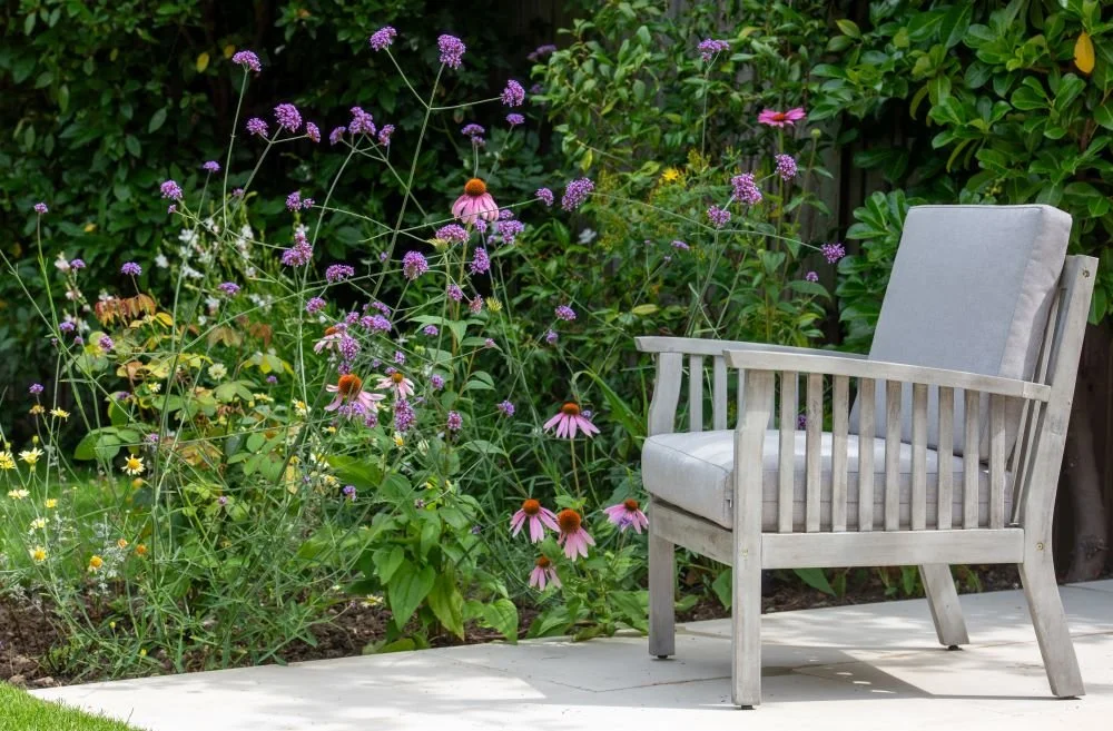 Wooden armchair on a stone patio beside a naturalistic flower border in a Wimbledon garden

A comfortable outdoor armchair sits on the stone terrace, angled towards a billowing border of echinacea and verbena — a quiet spot to enjoy the garden, desig