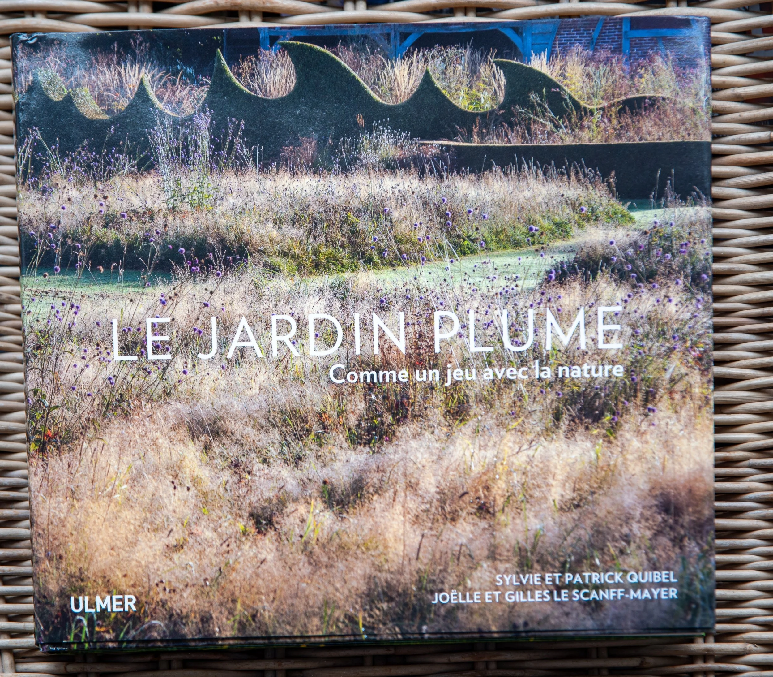 The book cover of 'Le Jardin Plume', showing wave-shaped clipped hedges rising above a meadow of ornamental grasses.