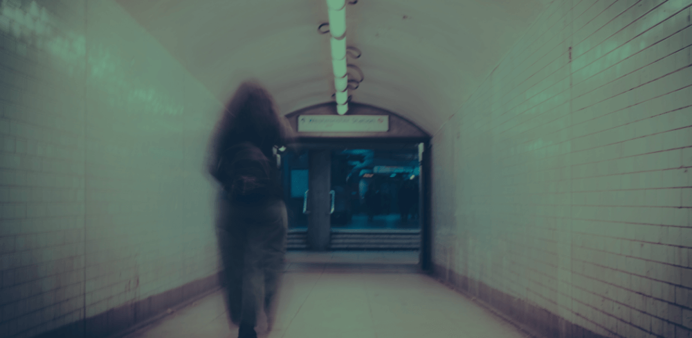 Woman walking through a train station towards an exit.