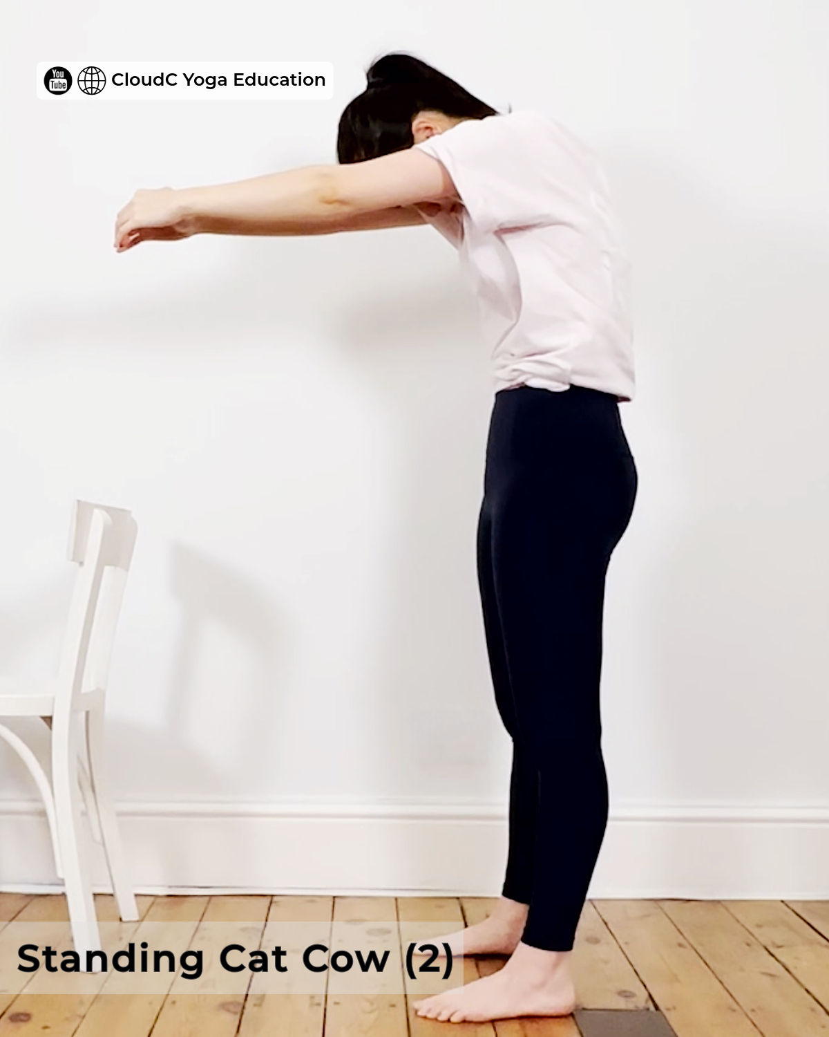 Woman practising standing cat cow, back rounded forward with arms extended, beginner yoga pose for back pain