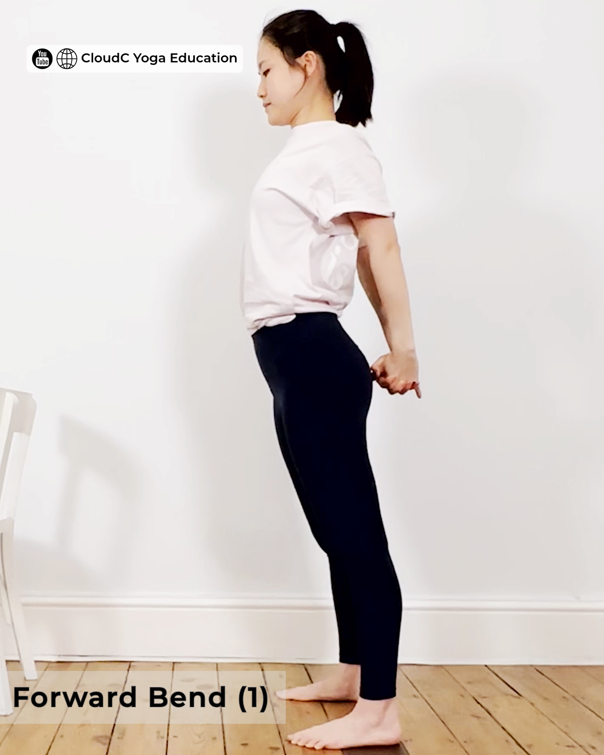Woman standing with fingers interlaced behind her back, shoulders gently rolled back, preparing for a forward bend