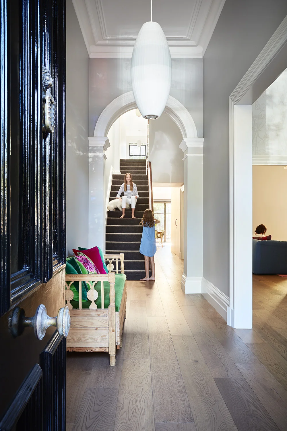 This boom-time terrace in Melbourne's inner north under-took a significant overhaul as the internal spaces were opened up to create connection and flow throughout an a previously internal and dark Victorian interior. Significant heritage listings prevented any significant external works. A black steel, contemporary window box punctures the rear north-facing facade, and takes advantage of the northern orientation. Formal reception rooms were given a new lease of life, with new openings made onto the grand hallway with colour, wall paper and decoration being embraced. Kitchens and bathrooms are clean and bright, while keeping the palette simple and refined. This old dame now has been given a new life as a contemporary family home that embraces and celebrates its past and future.