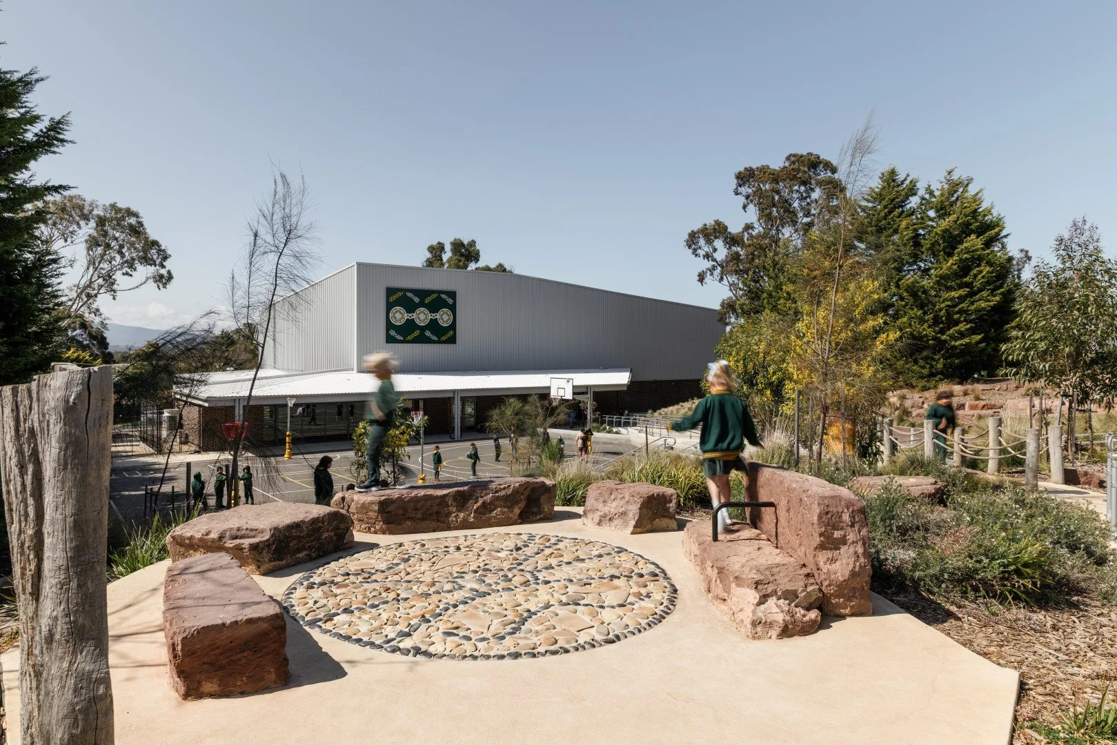  The design expresses its dual purpose through two distinct frontages. A clear and welcoming public entry, defined by three circular windows referencing the Olympic rings, faces the community, while the school-facing elevation opens via large sliding