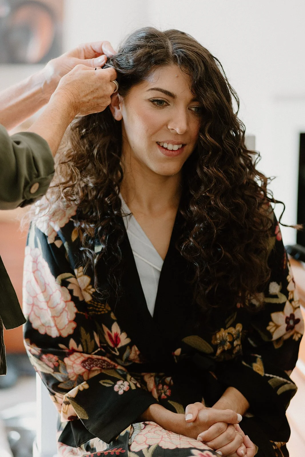 Bride with long naturally curly hair. Bridal hair stylist (specialising in curly hair)pinning it back on one side. Photographer-Libby Christensen