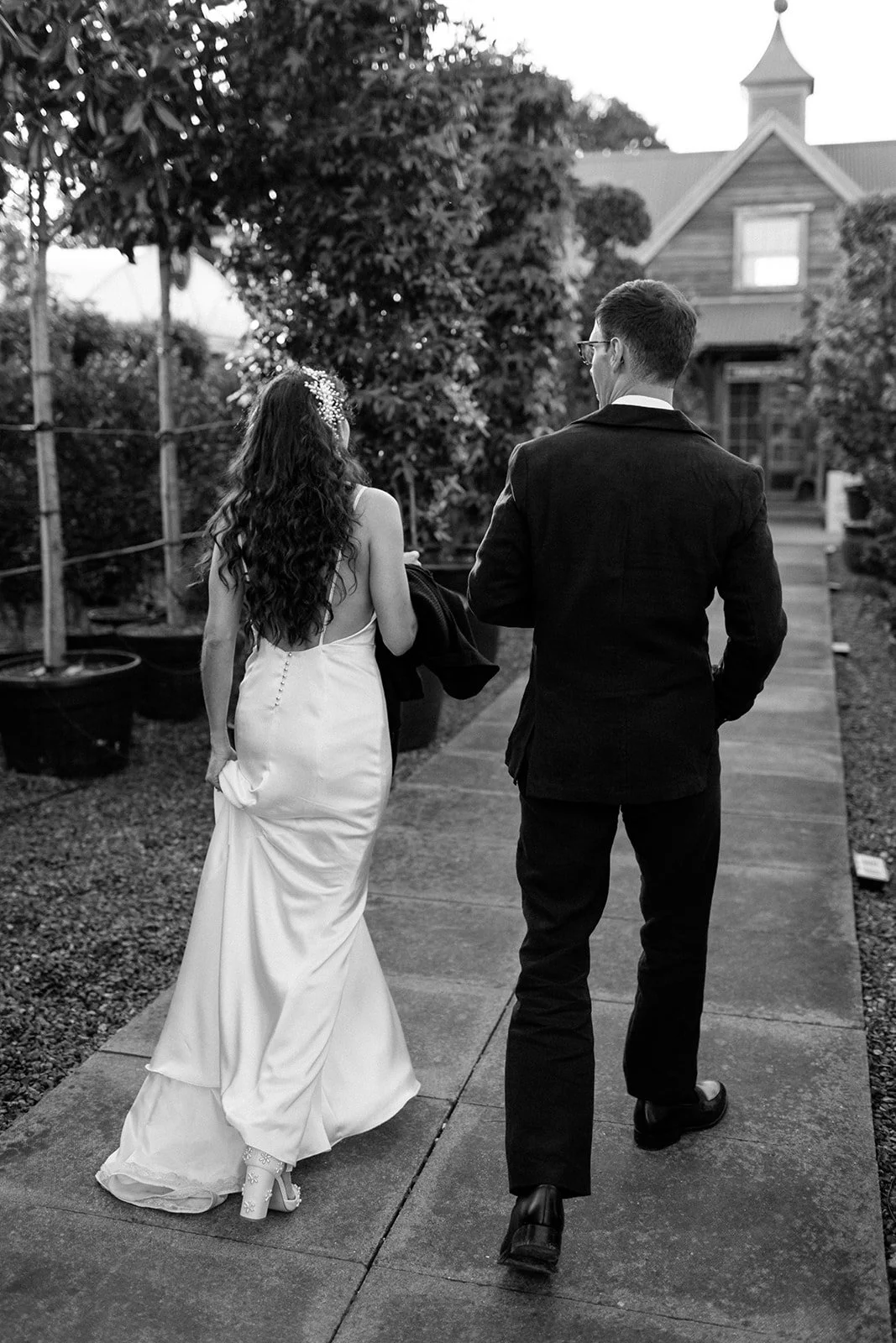 Naturally curly long dark haired bride, holding her dress. walking away with her husband.
Image by Libby Christensen Photography