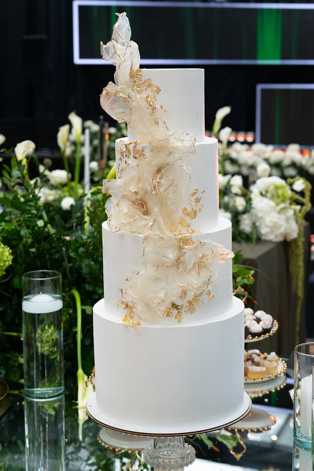 White wedding cake with gold details surrounded by white flowers