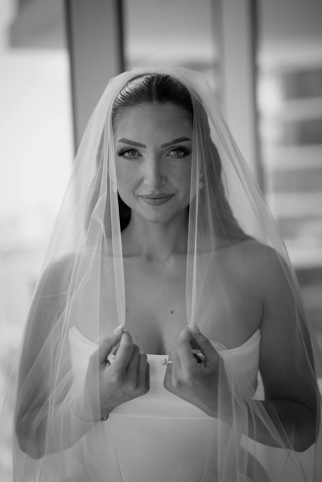 Black and white portrait of Rachel holding her veil before her Church of the Epiphany wedding in Miami