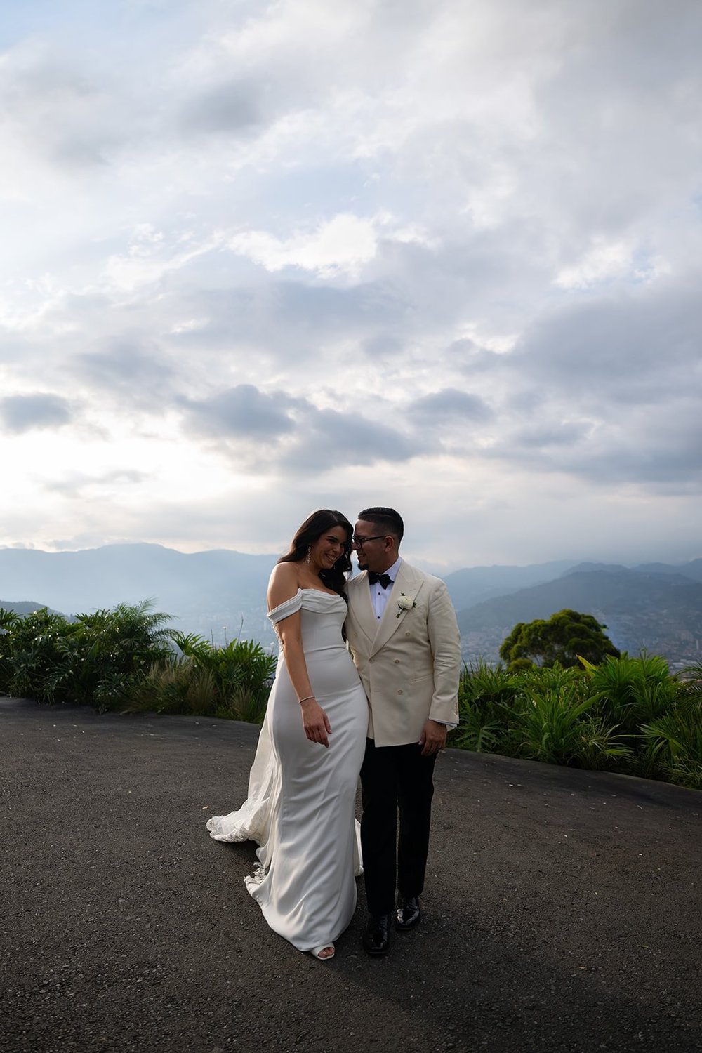 Krystine and Douglas standing together on a road with cloudy mountains behind them