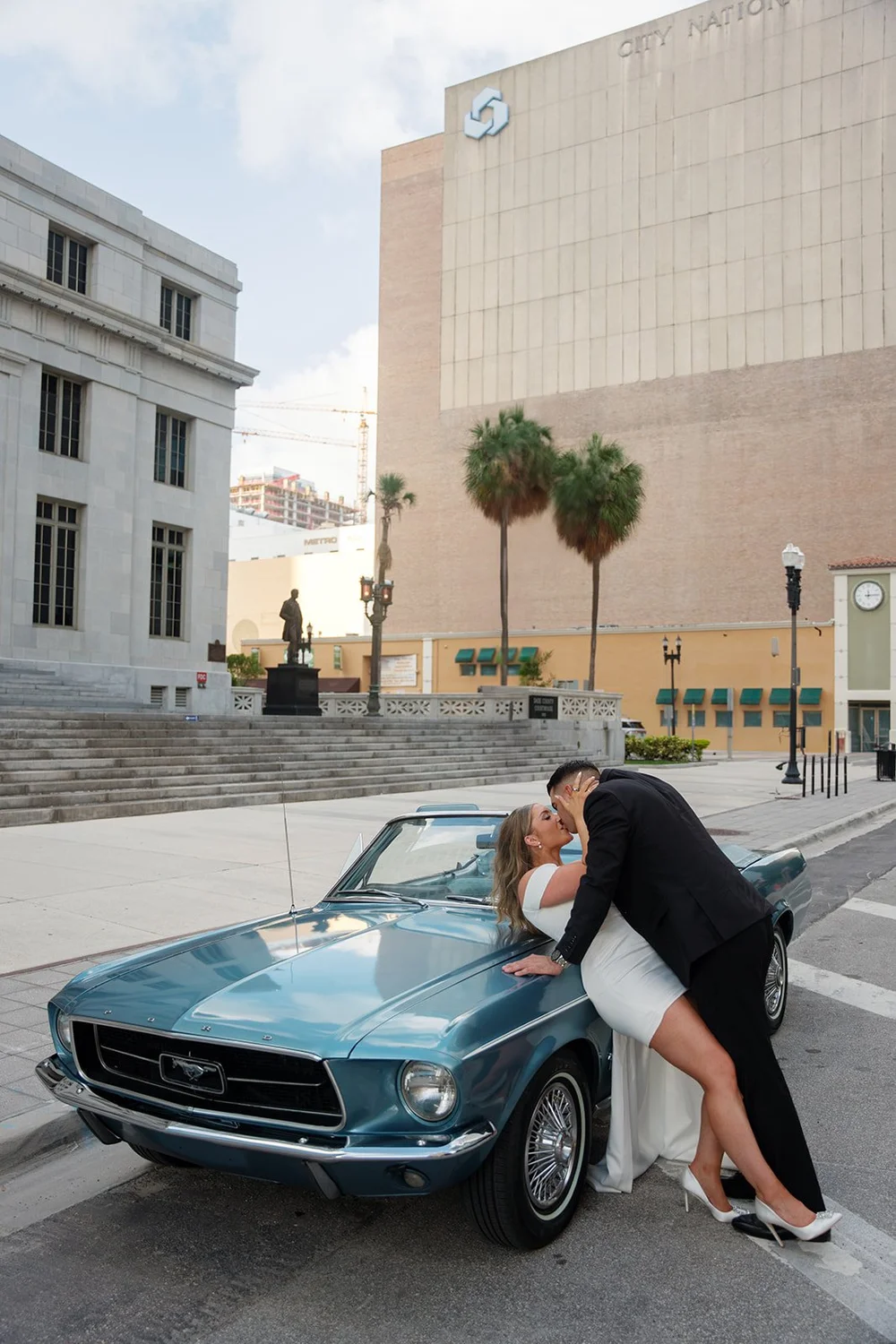 Austin leaning Rachel back for a kiss on the hood of the blue Mustang