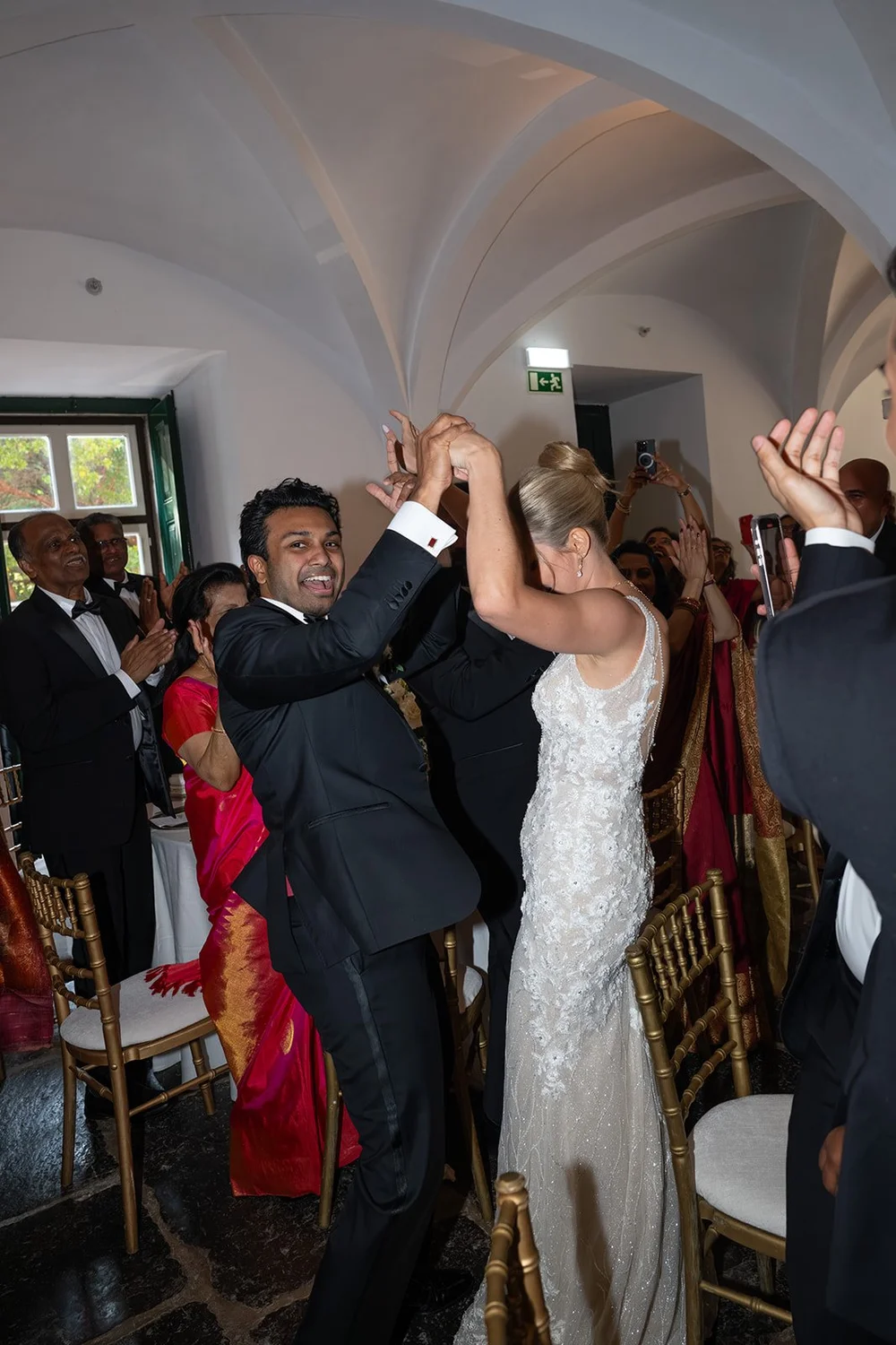 Ellen dancing with Jacob among cheering guests under the arches at the reception