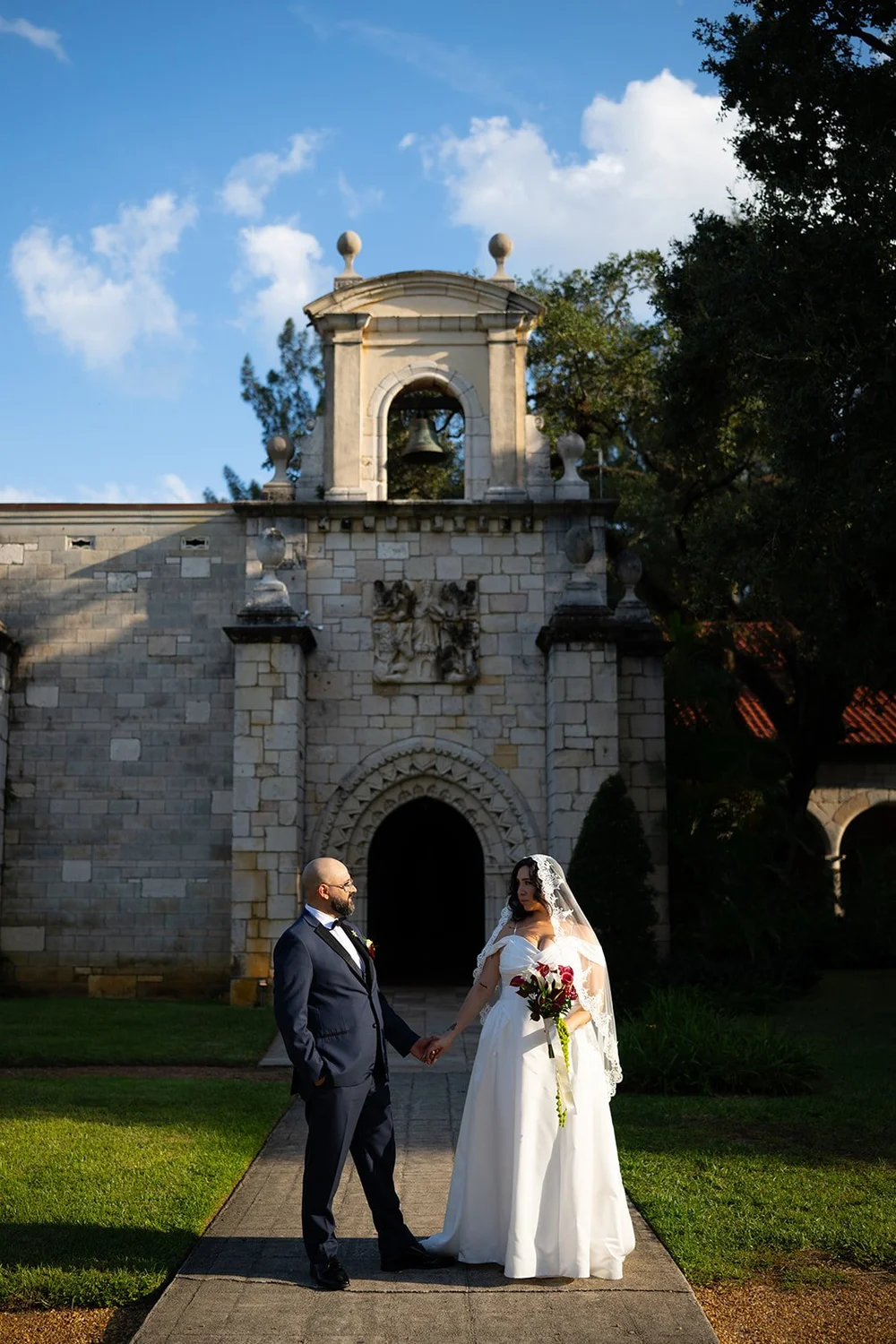 Maria and Christian standing in front of the stone tower at the monastery entrance