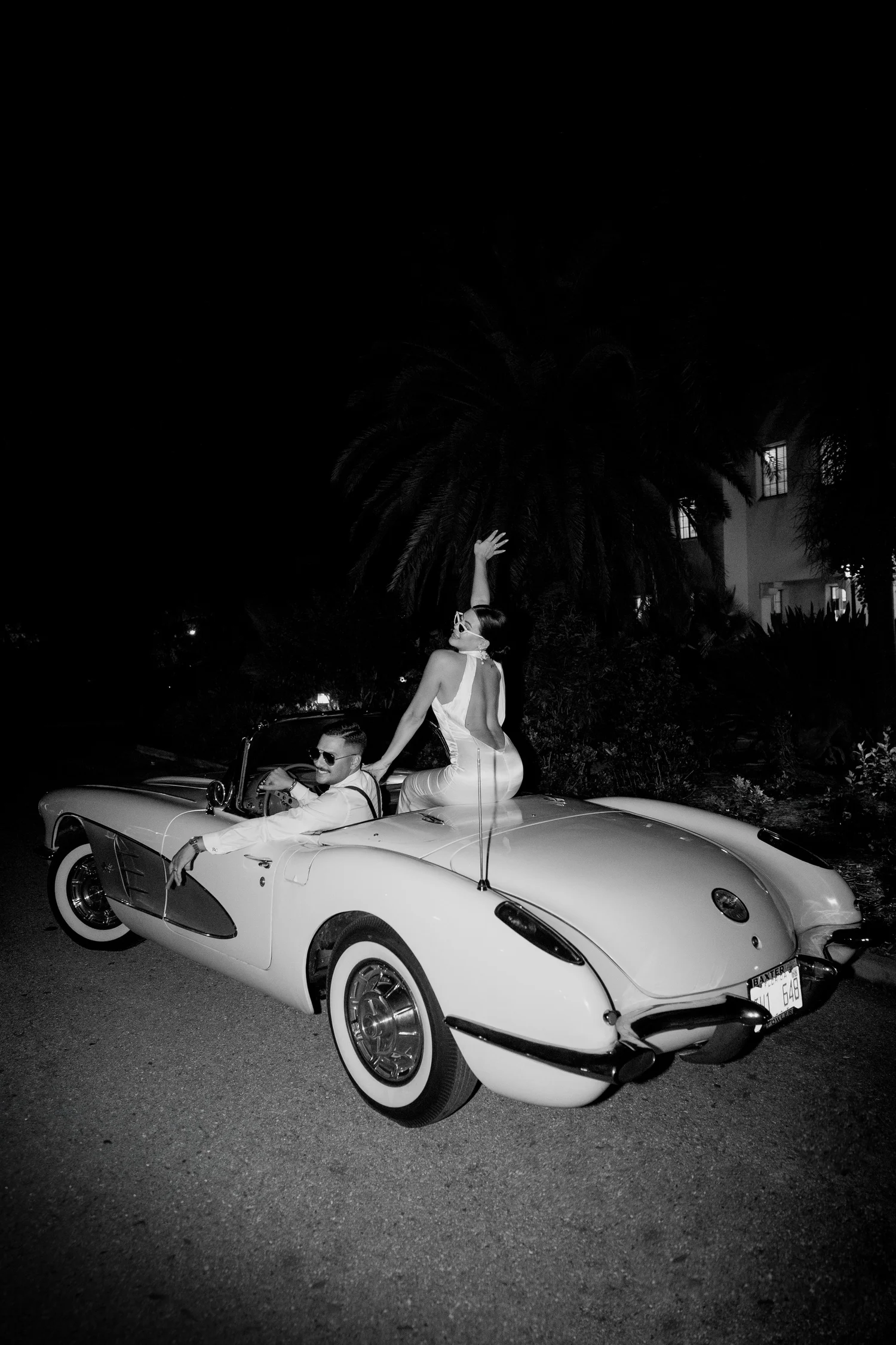 Bride and groom in a vintage convertible at night