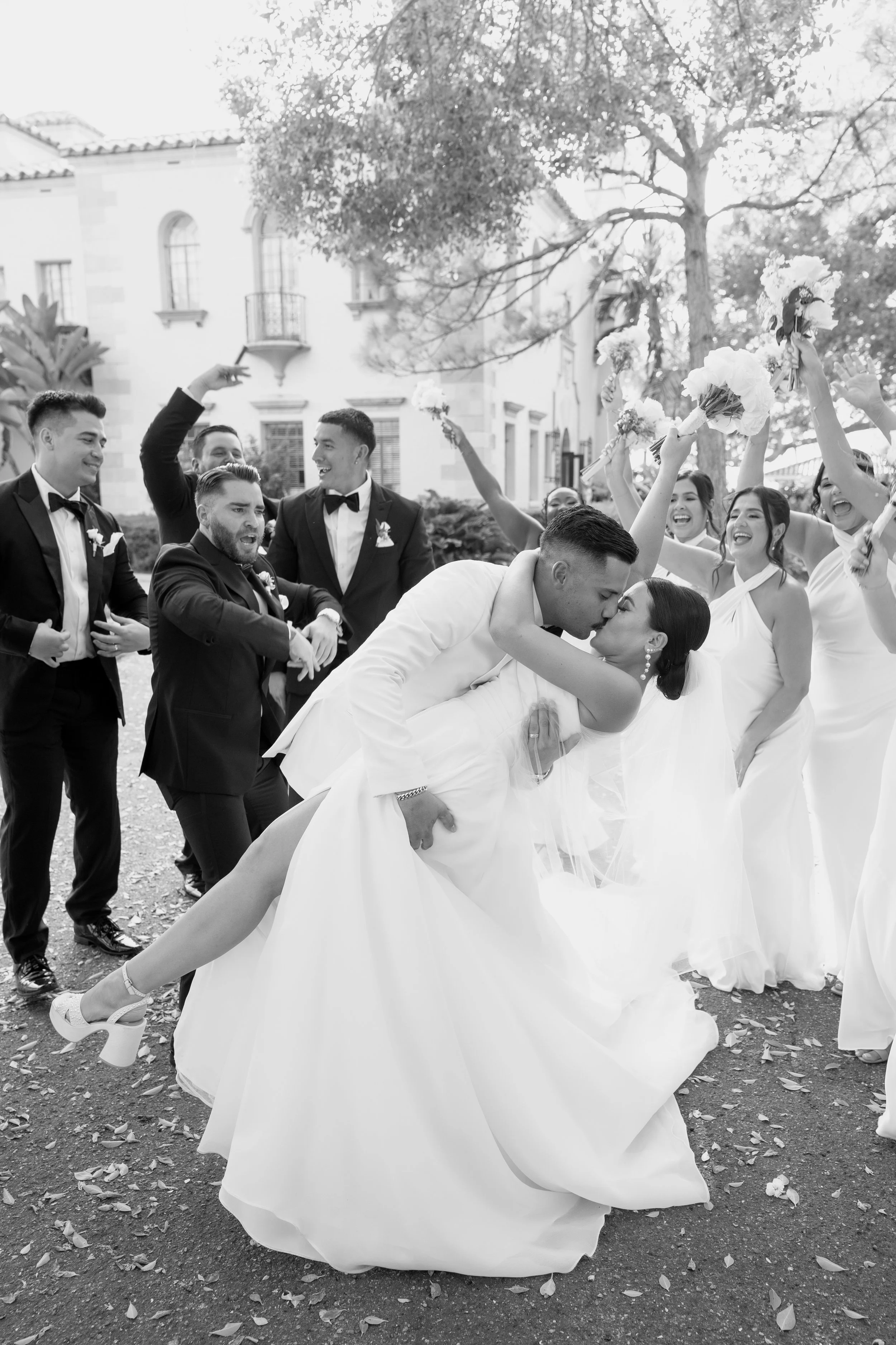 Bride and groom kissing as guests celebrate around them at a Miami wedding