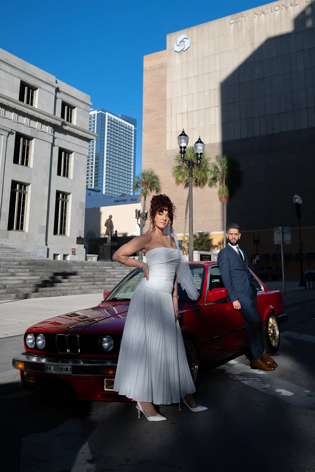 Bride and groom with a red BMW after their Miami courthouse wedding