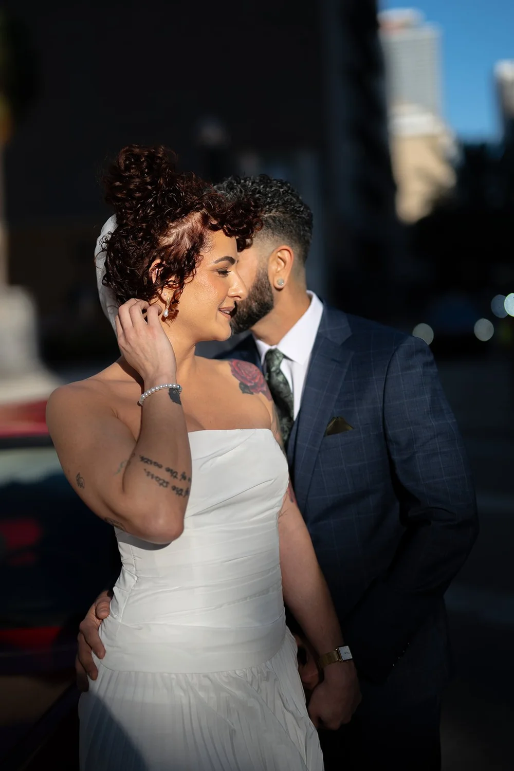 Bride touching her hair as she and the groom kiss in downtown Miami