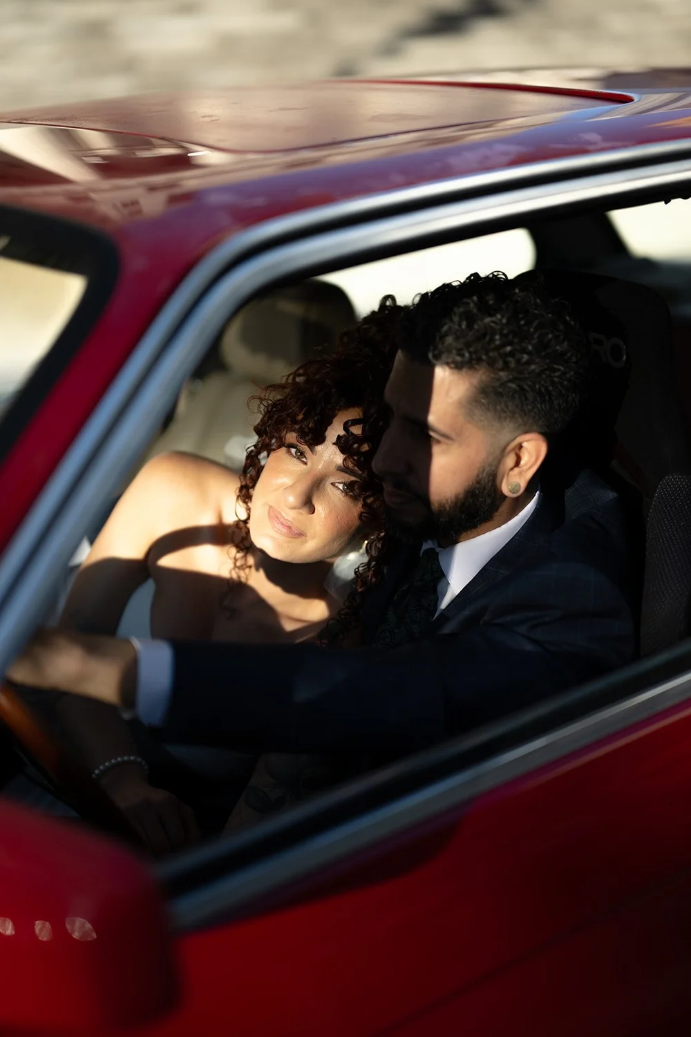 Bride and groom kissing inside the red BMW