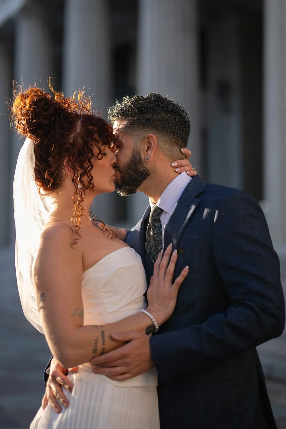 Bride and groom kissing in front of tall stone columns