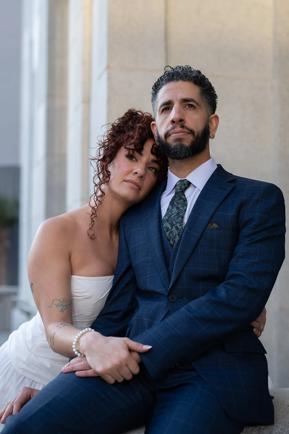 Groom in a navy suit seated beside the bride, looking toward the camera