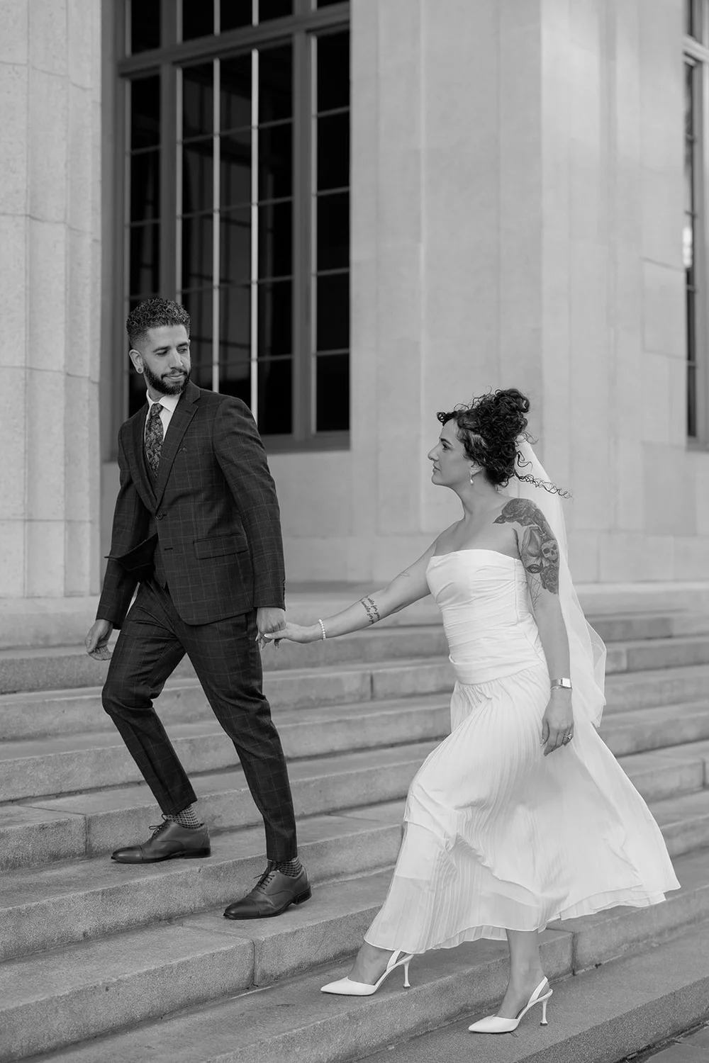 Black and white photo of the groom and bride climbing the courthouse steps hand in hand