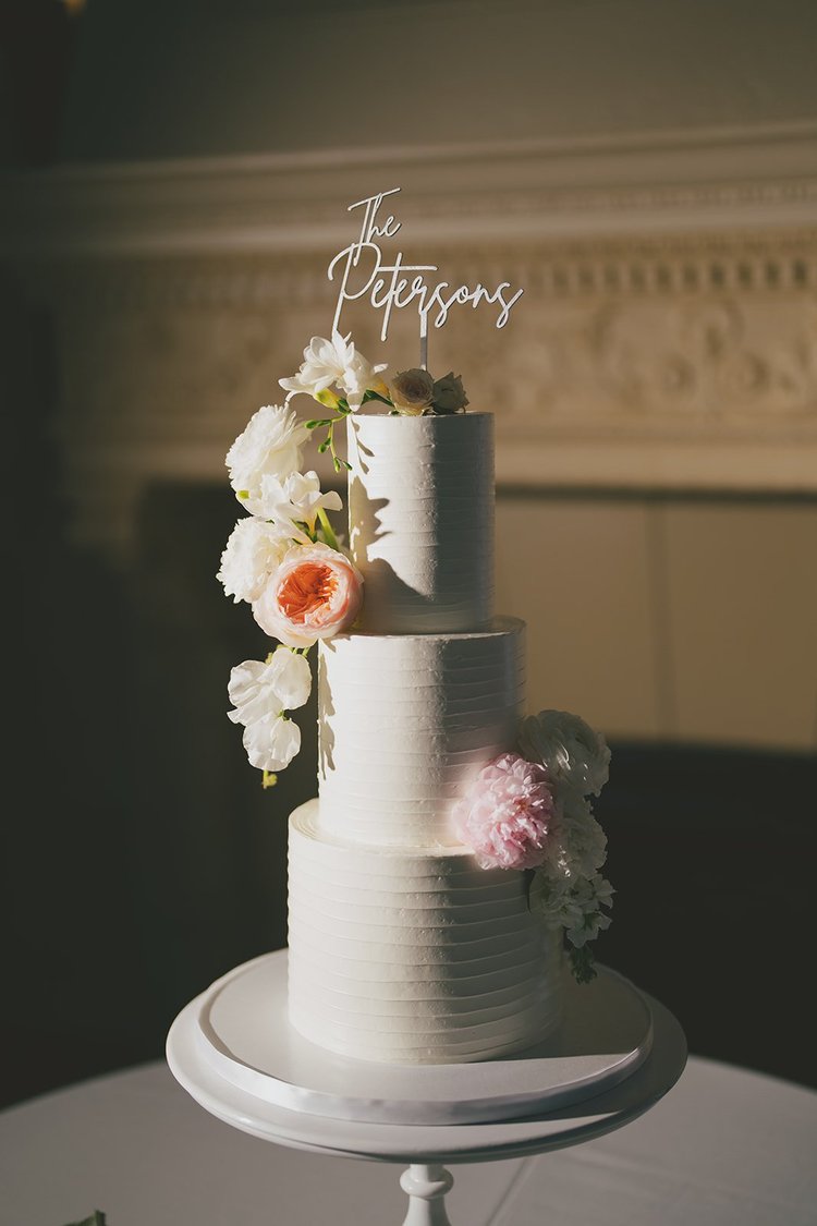 Film photo of a three-tier white wedding cake with flowers and a cake topper