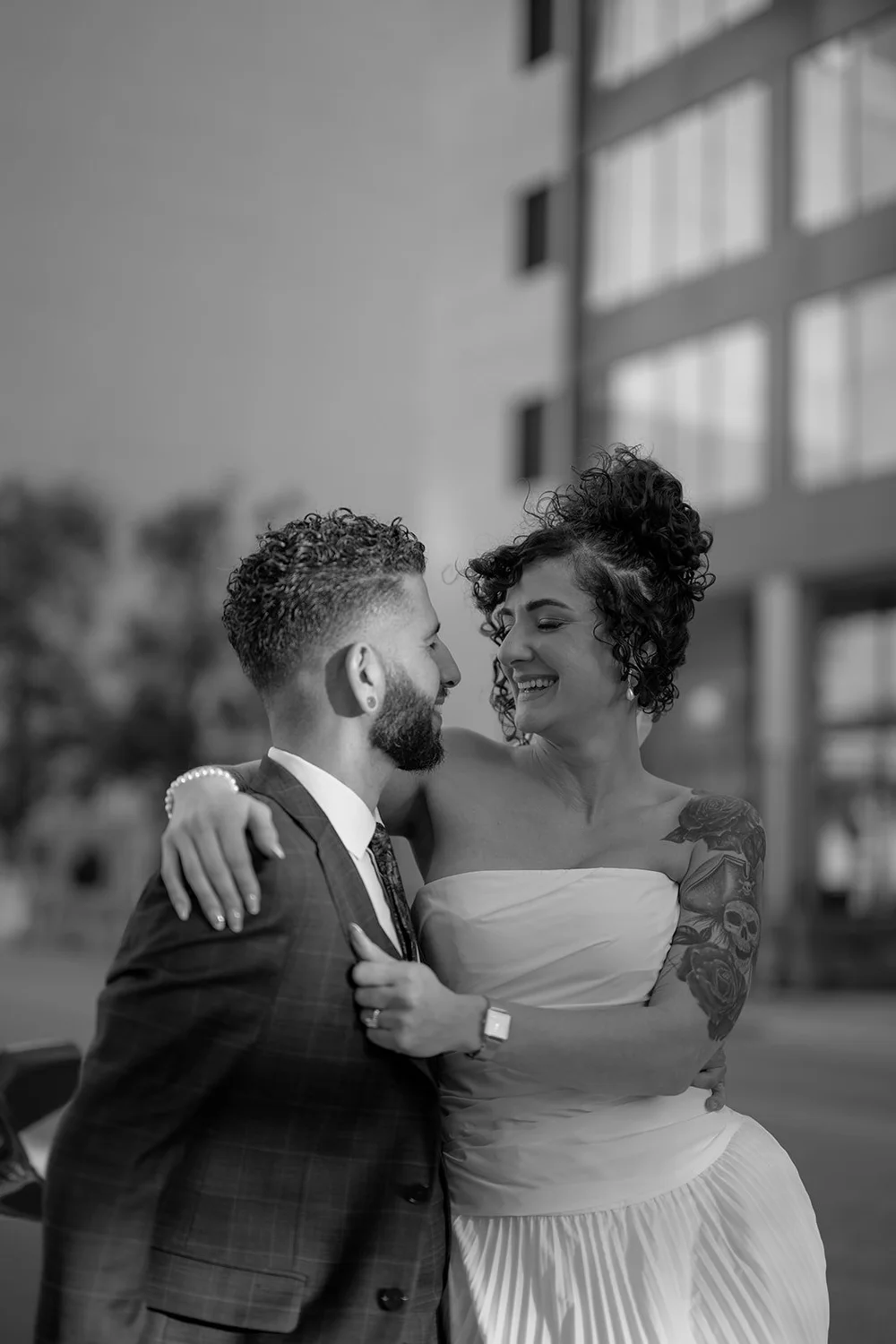 Black and white photo of the groom and bride smiling in an embrace on a downtown Miami street