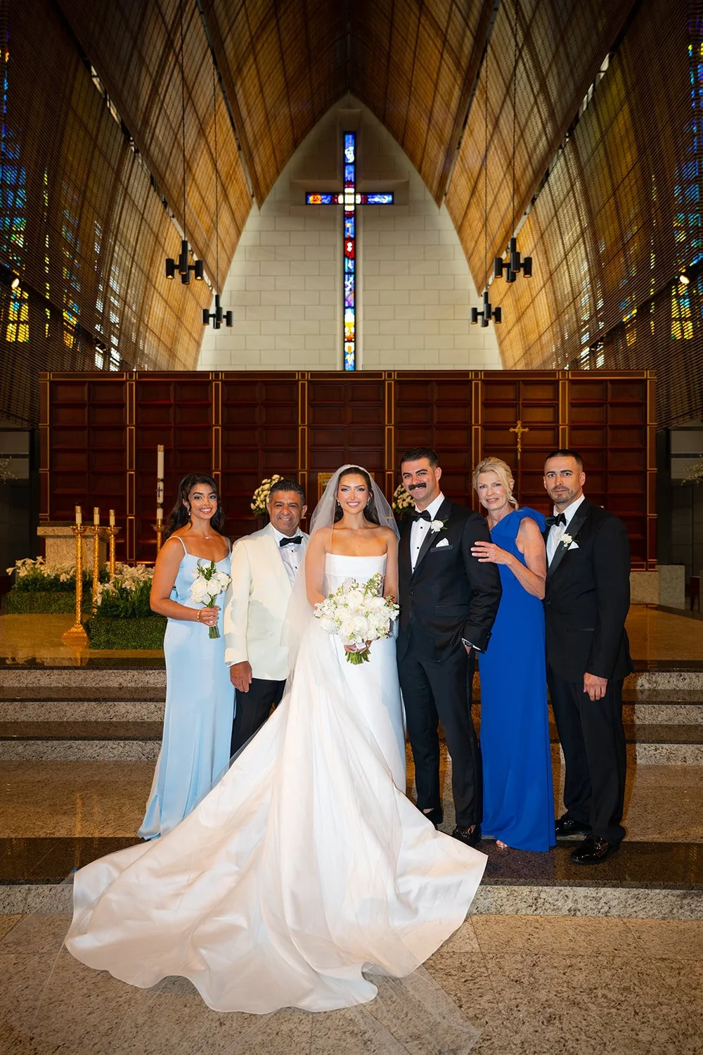 Rachel and Austin with bridesmaids in light blue and groomsmen in black on the church altar steps