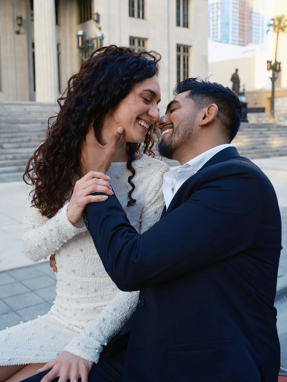 Bride and groom laughing in an embrace on a downtown Miami street