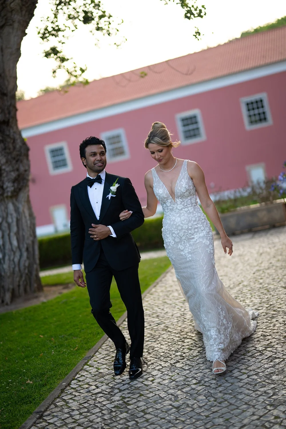 Ellen and Jacob walking along a stone path in front of a pink building