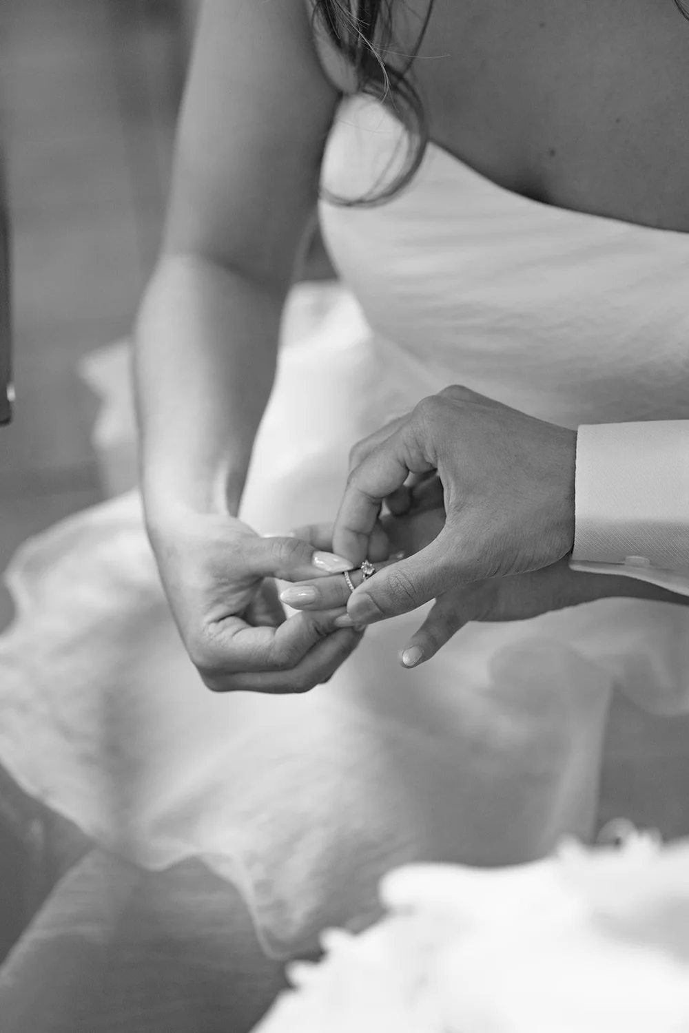 Black and white close-up of the couple's hands together with wedding rings, Chris's white skirt below