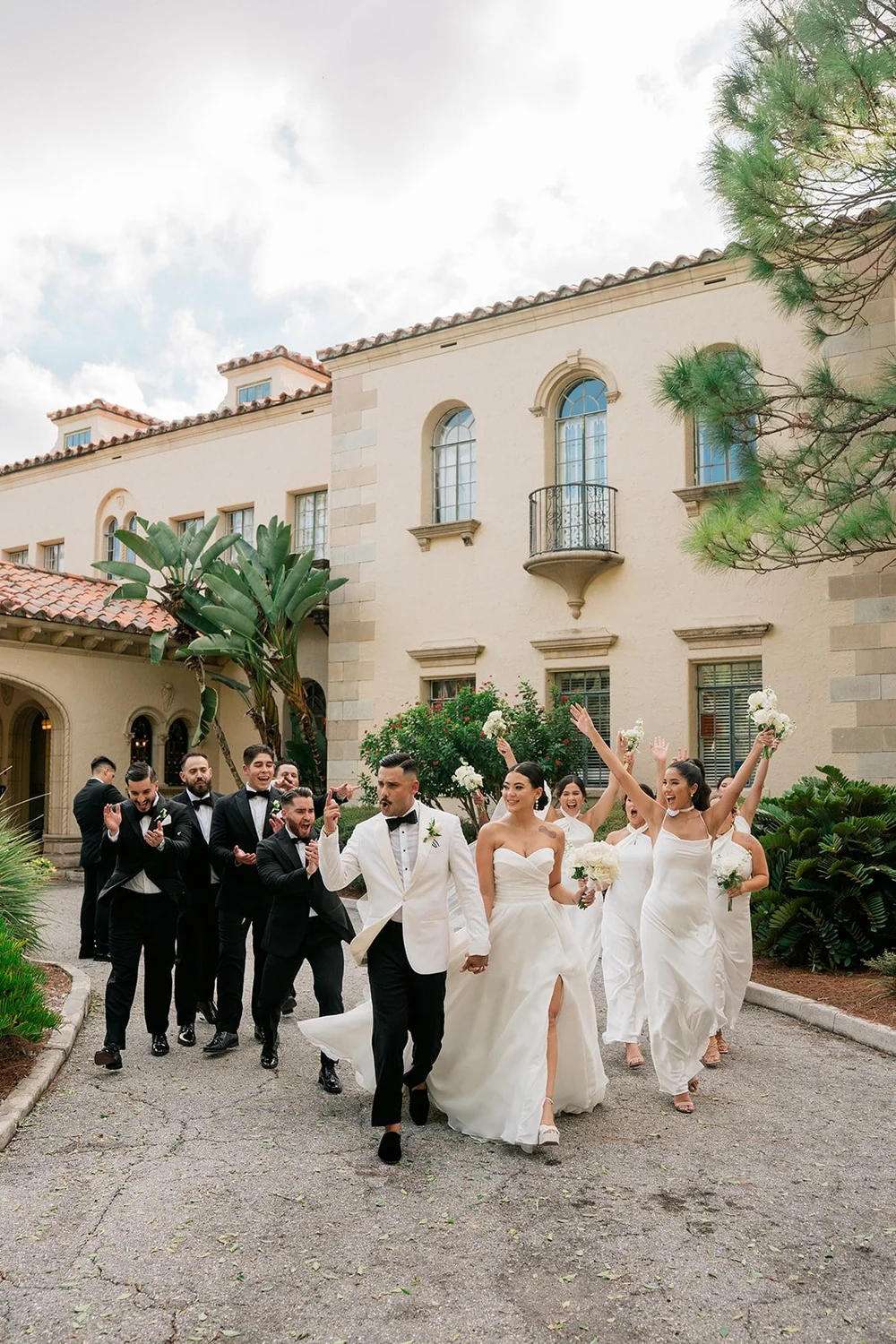 Steph and Ricky leading their wedding party down the driveway in front of the Powel Crosley Estate house in Sarasota