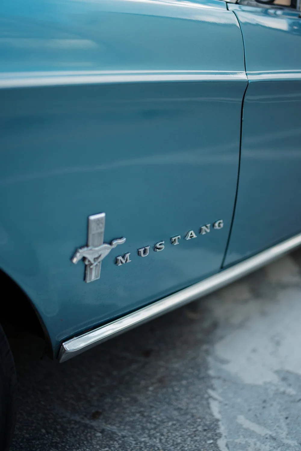 Detail of the Mustang badge on the side of the blue convertible