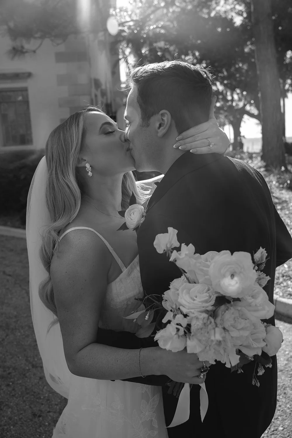 Black and white photo of Jane and Berkeley kissing while she holds her bouquet