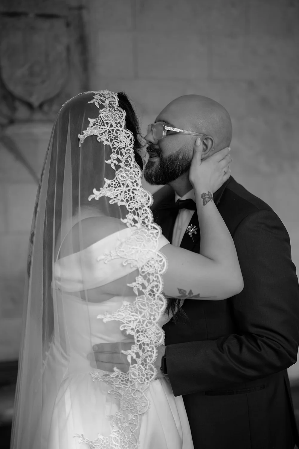 Christian kissing Maria's cheek as she touches his face, close portrait in black and white
