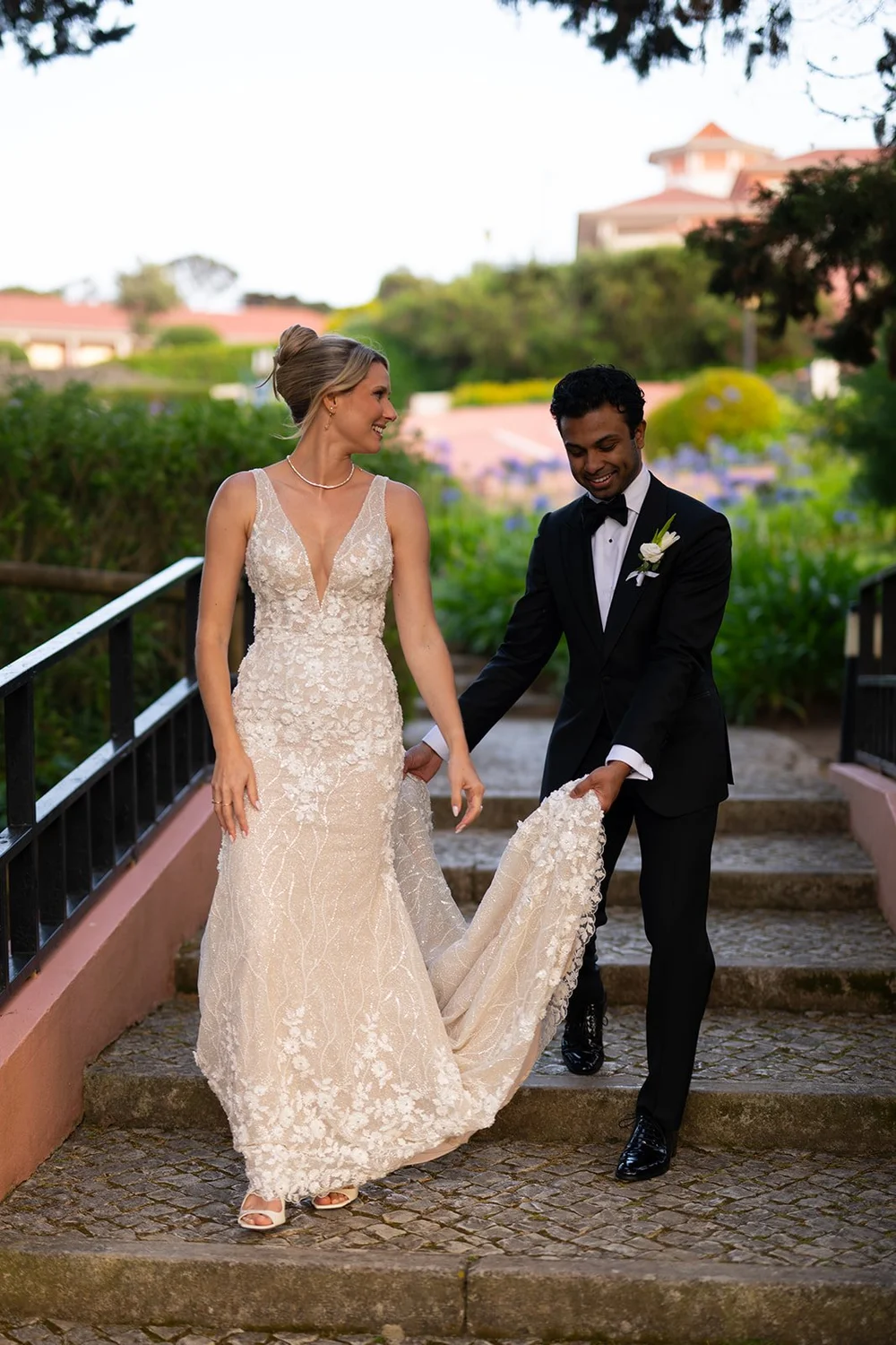 Jacob holding the train of Ellen's dress as they walk down stone steps
