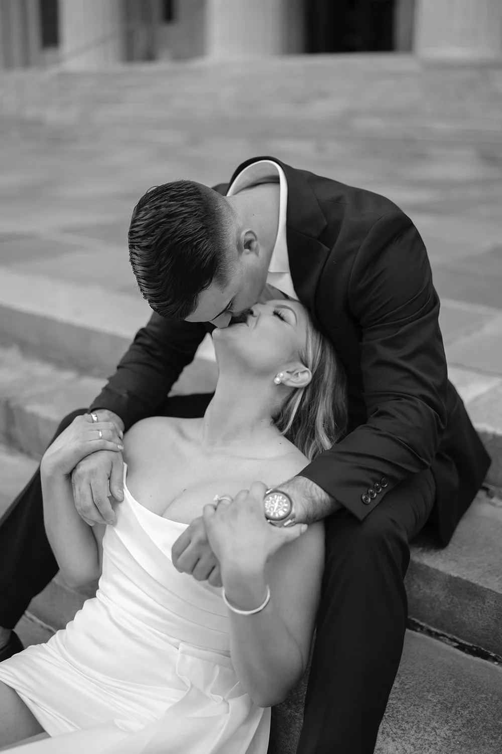 Austin leaning over Rachel in a close black and white portrait on the stone steps
