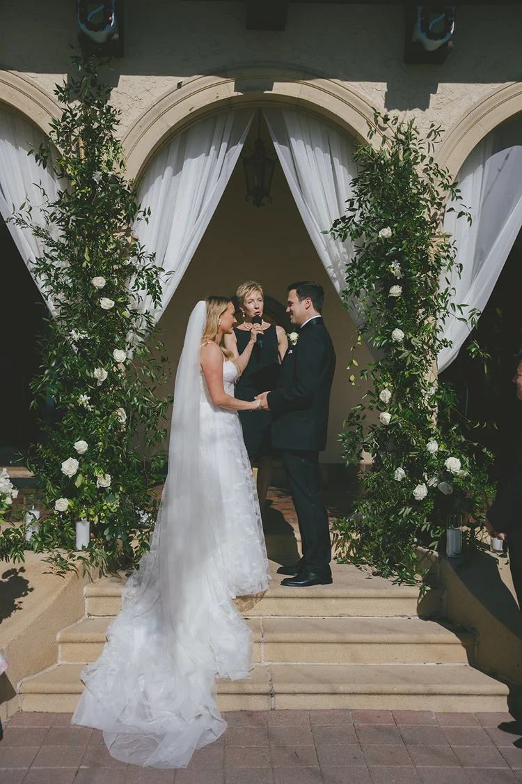 Film photo of Jane and Berkeley standing under a ceremony arch of greenery and white drapes