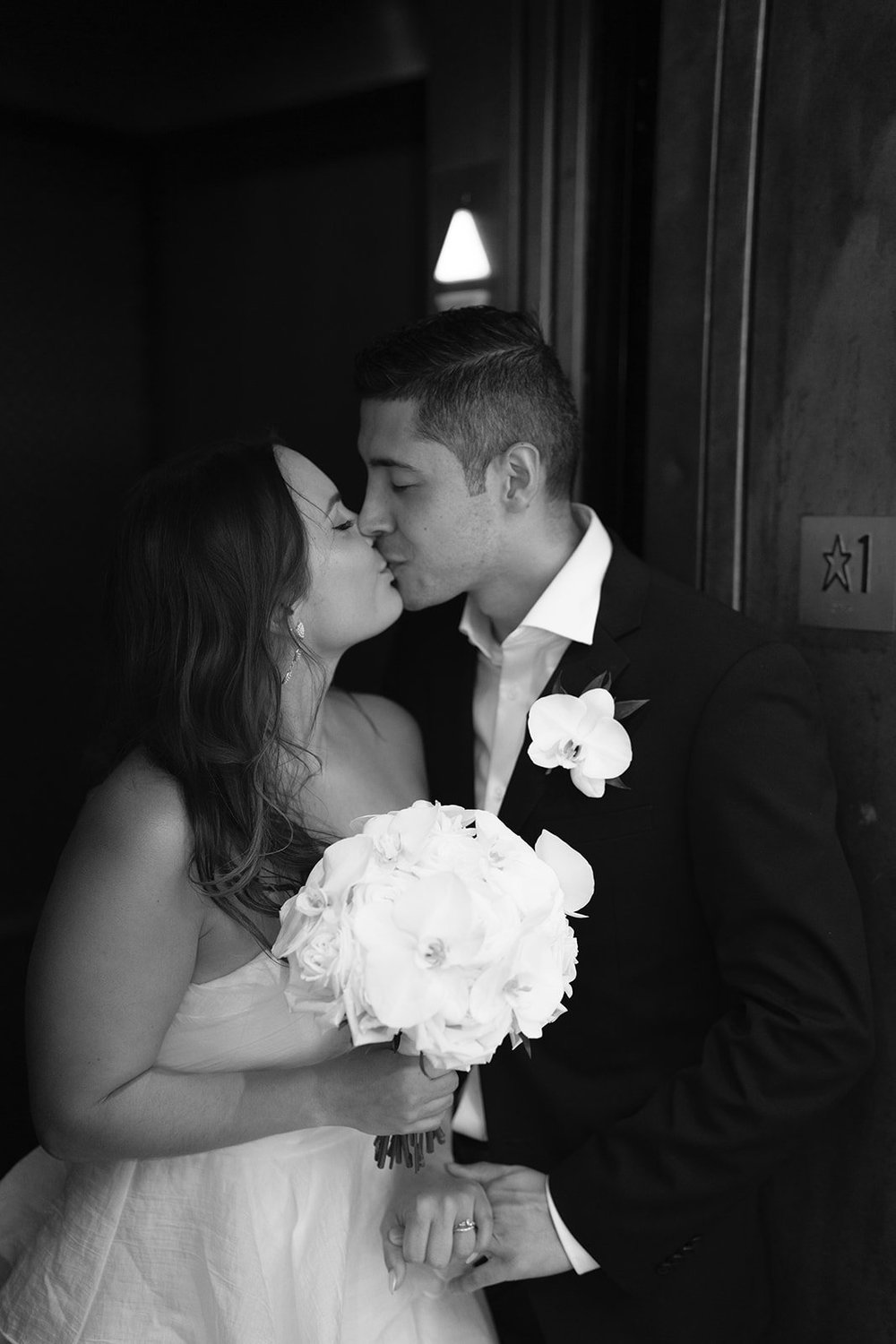 Black and white close shot of the couple kissing, Chris's white bouquet in front of her