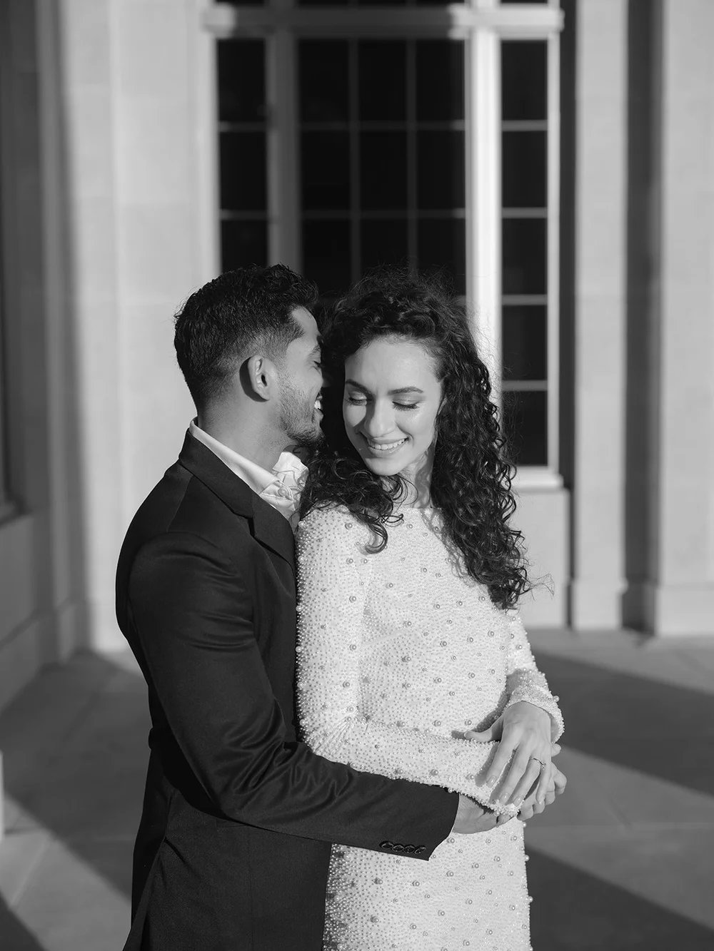 Black and white portrait of the bride and groom standing close together, looking down