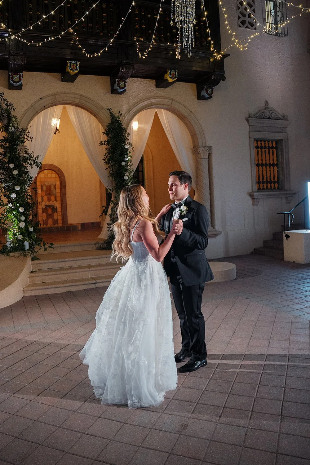 Jane and Berkeley dancing in the estate courtyard under string lights and arched doorways