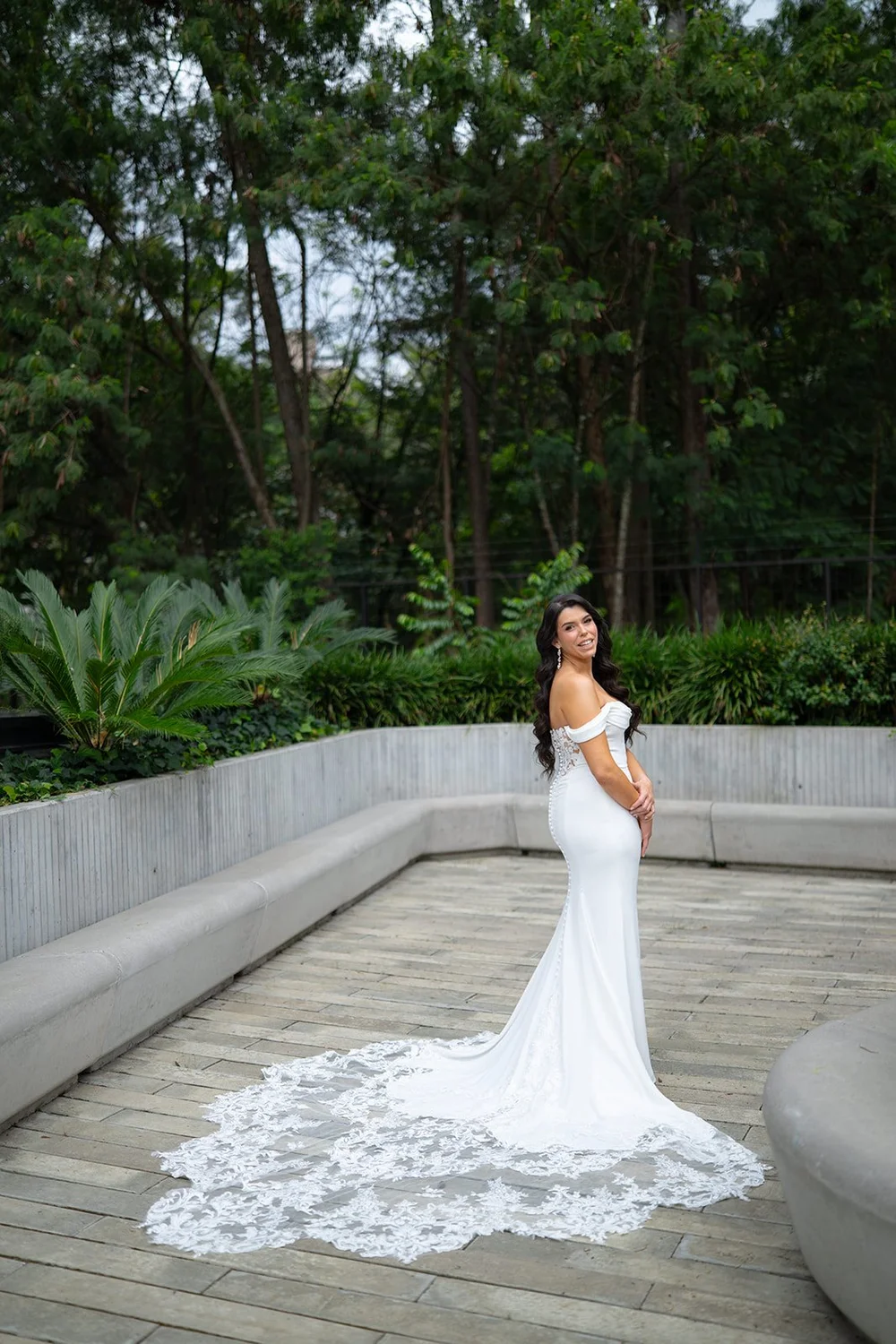 Krystine in her wedding gown with the lace train spread out behind her on the terrace