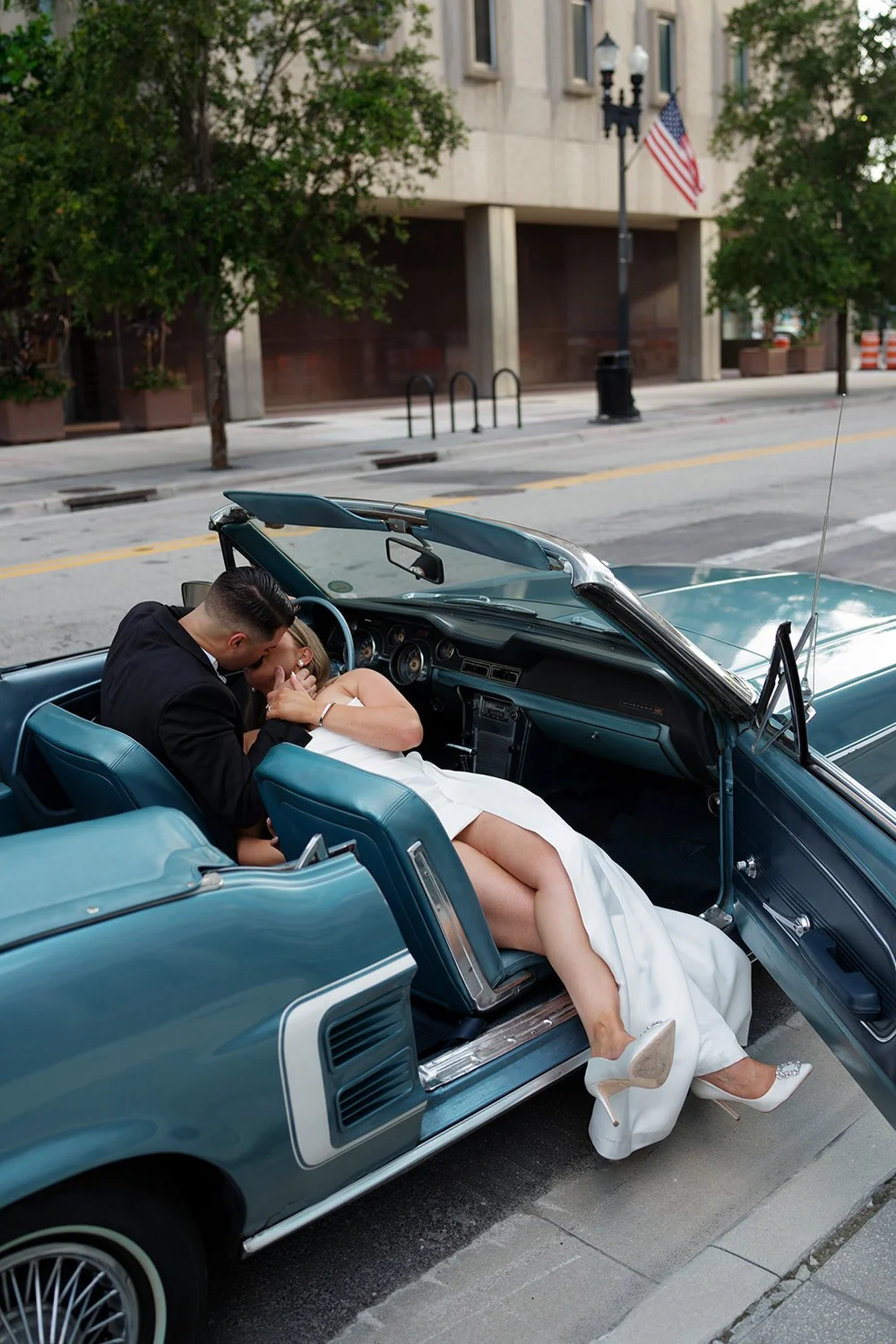 Rachel lying back across the front seat of the blue Mustang with Austin leaning over her