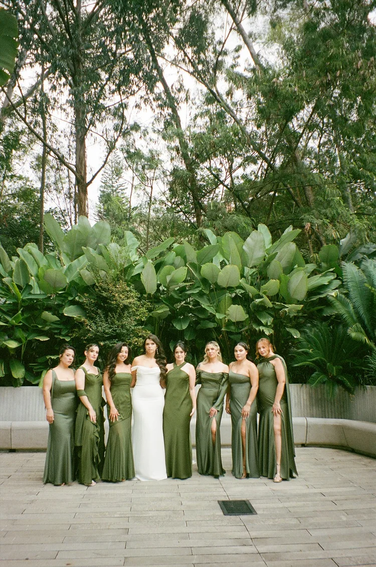 Film photo of Krystine with her bridesmaids in green dresses in front of tropical plants