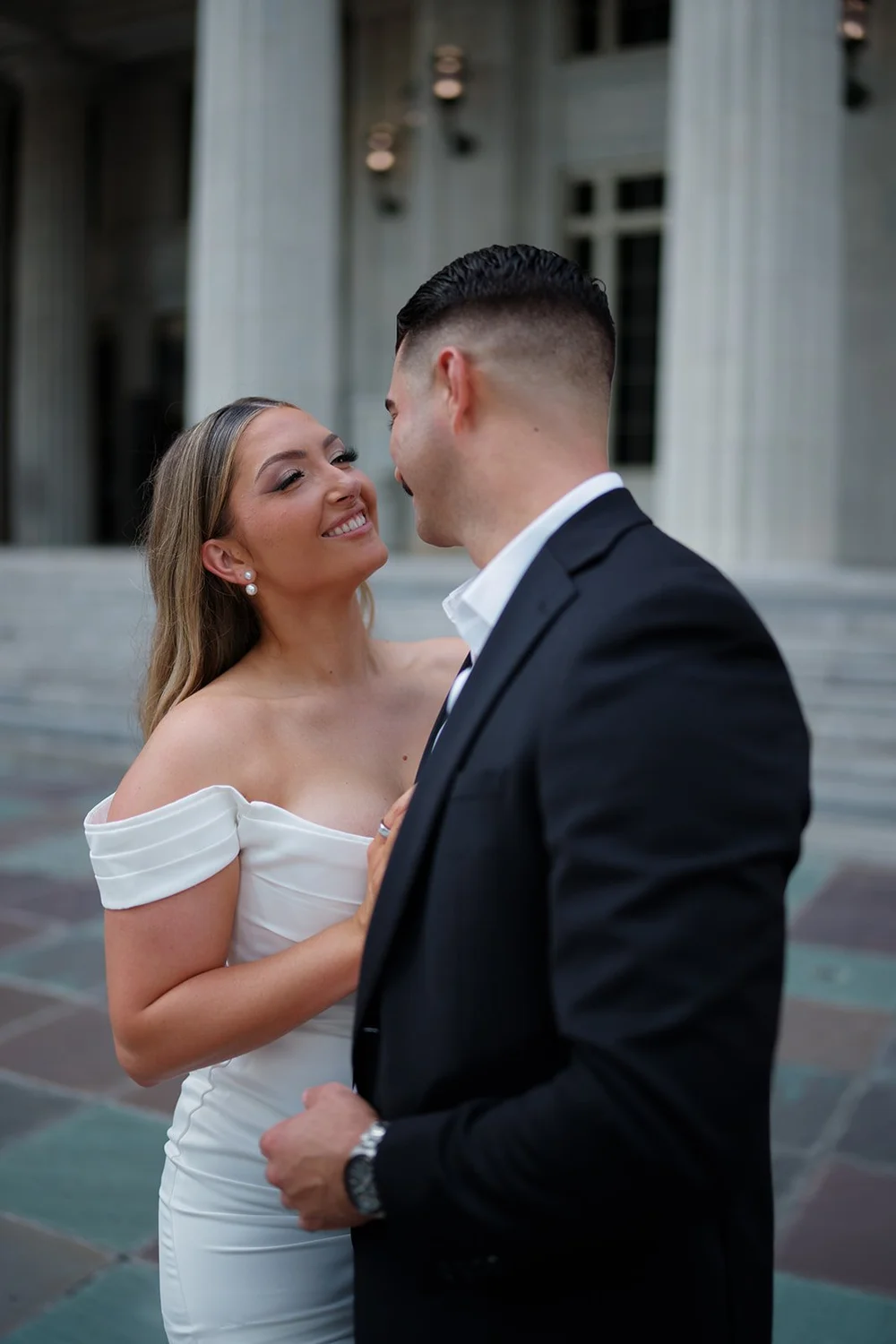 Rachel smiling at Austin in a close portrait with courthouse columns behind them