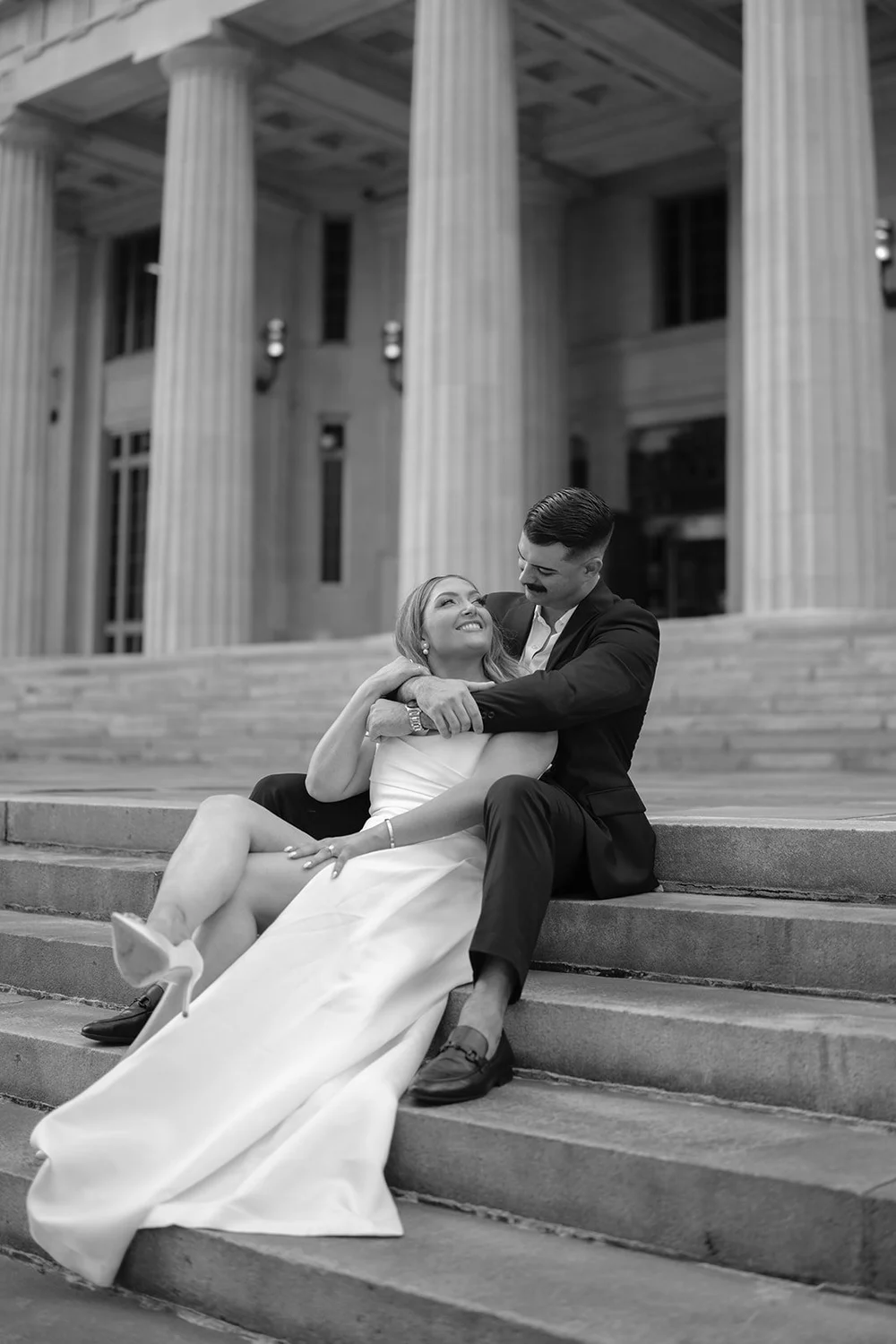 Rachel and Austin embracing on the courthouse steps in black and white